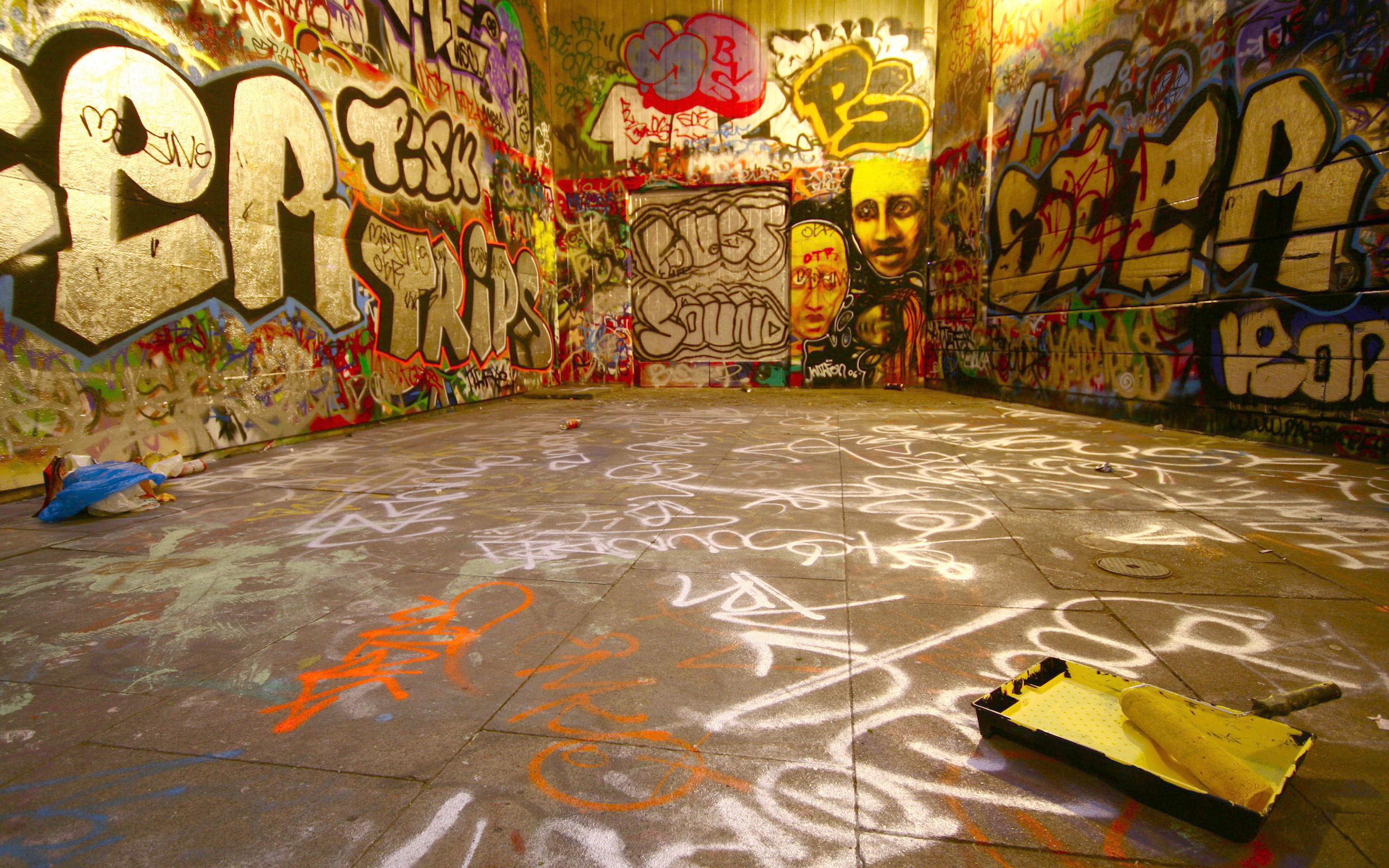 Graffiti-covered urban underpass with paint supplies HD Wallpaper