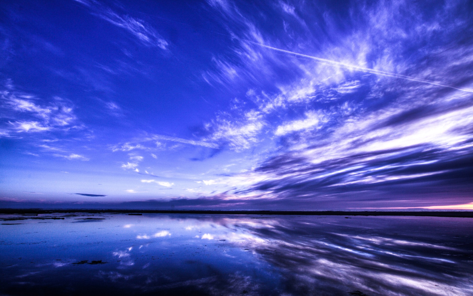 Vast blue sky with wispy clouds reflected in calm water HD Wallpaper