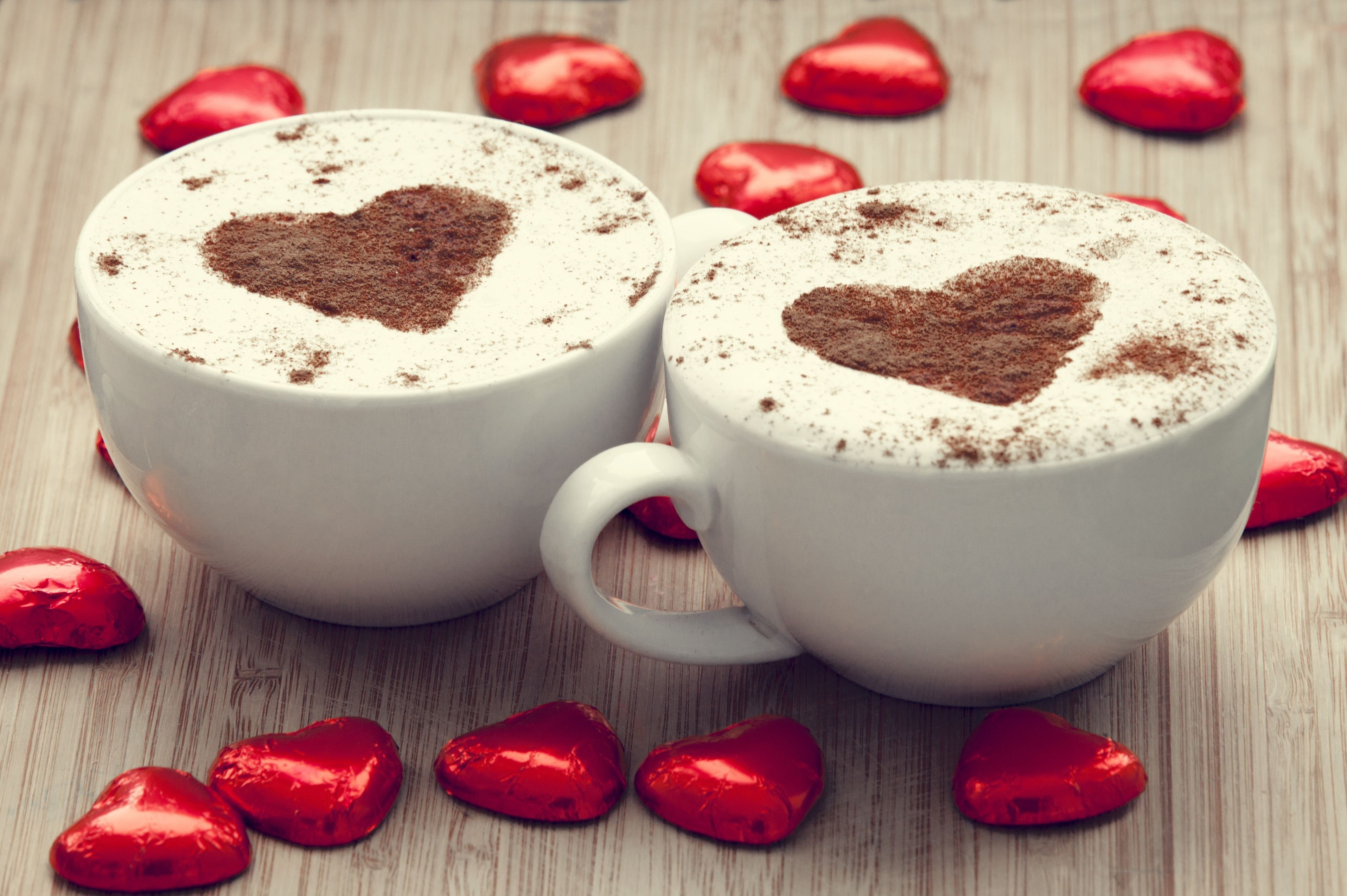 Two cups of coffee with heart art and chocolates HD Wallpaper