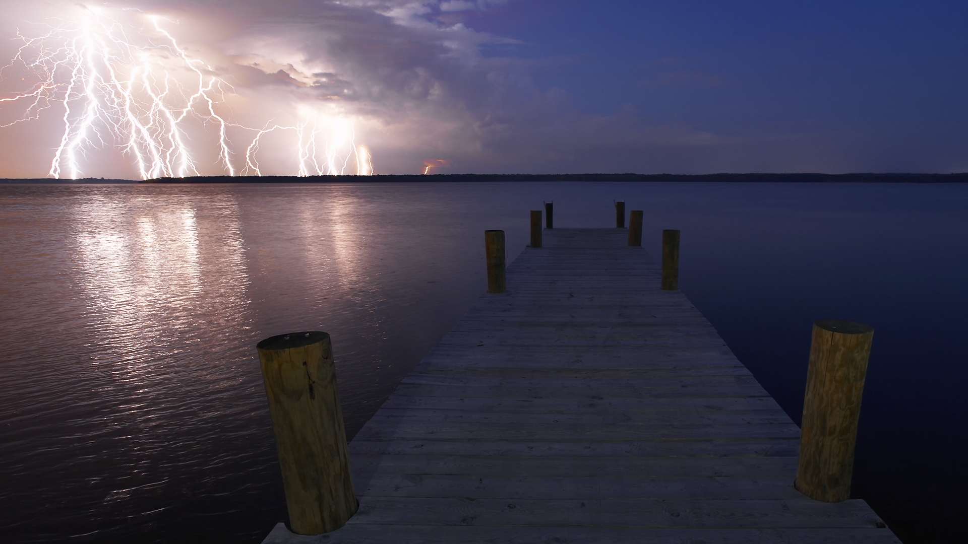 Lightning strikes over a lake with a wooden pier HD Wallpaper