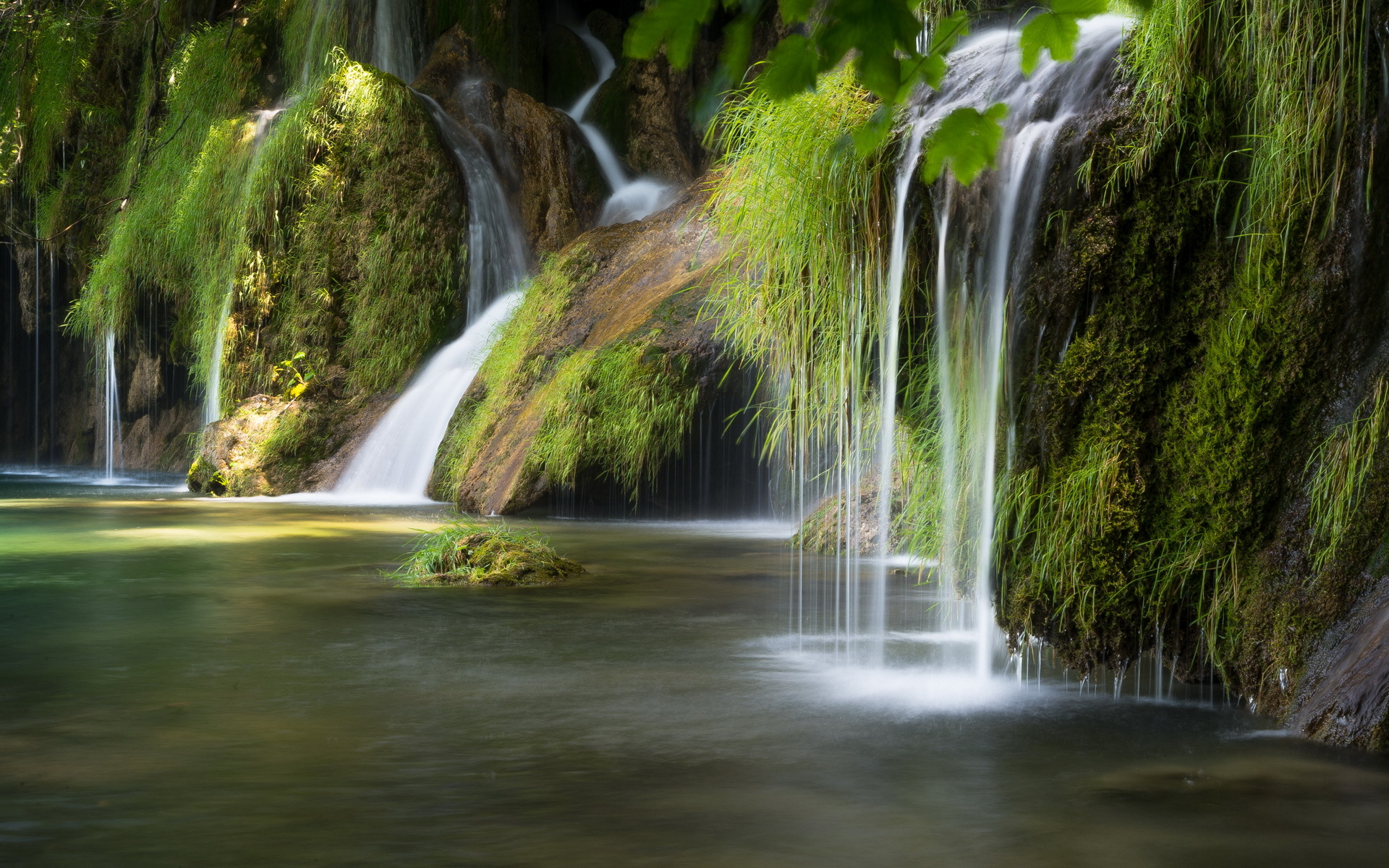 Waterfall cascading over mossy rocks into a pool HD Wallpaper
