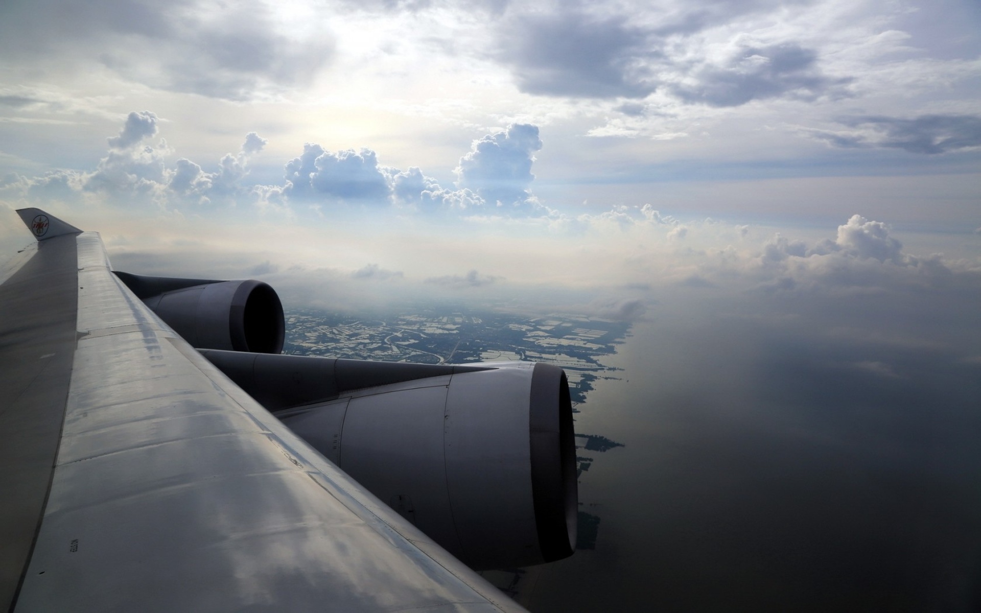 Airplane wing and engines flying over land and sea HD Wallpaper
