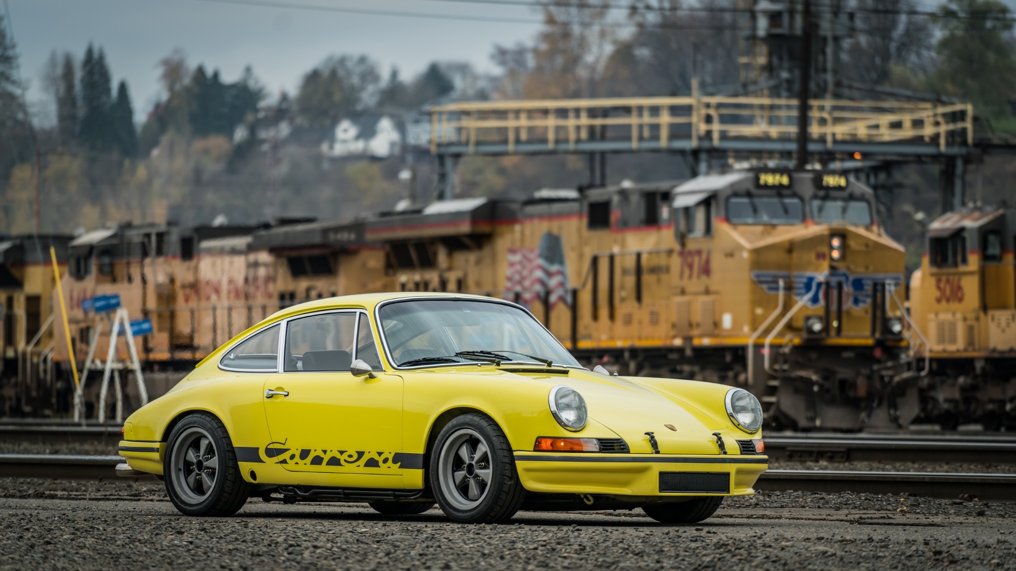 Yellow Porsche 911 Carrera T parked by trains HD Wallpaper
