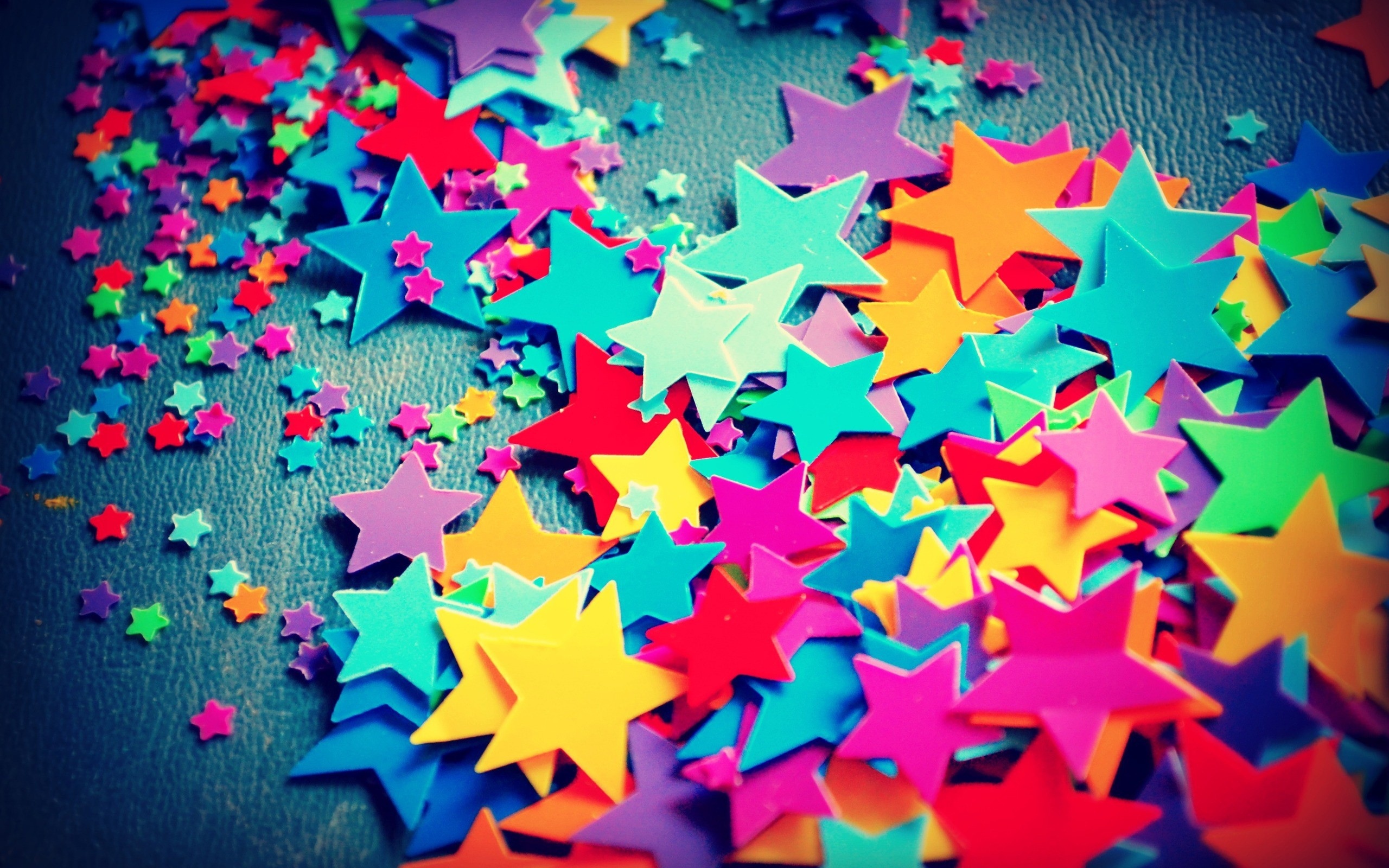 Colorful star confetti scattered on a dark surface HD Wallpaper