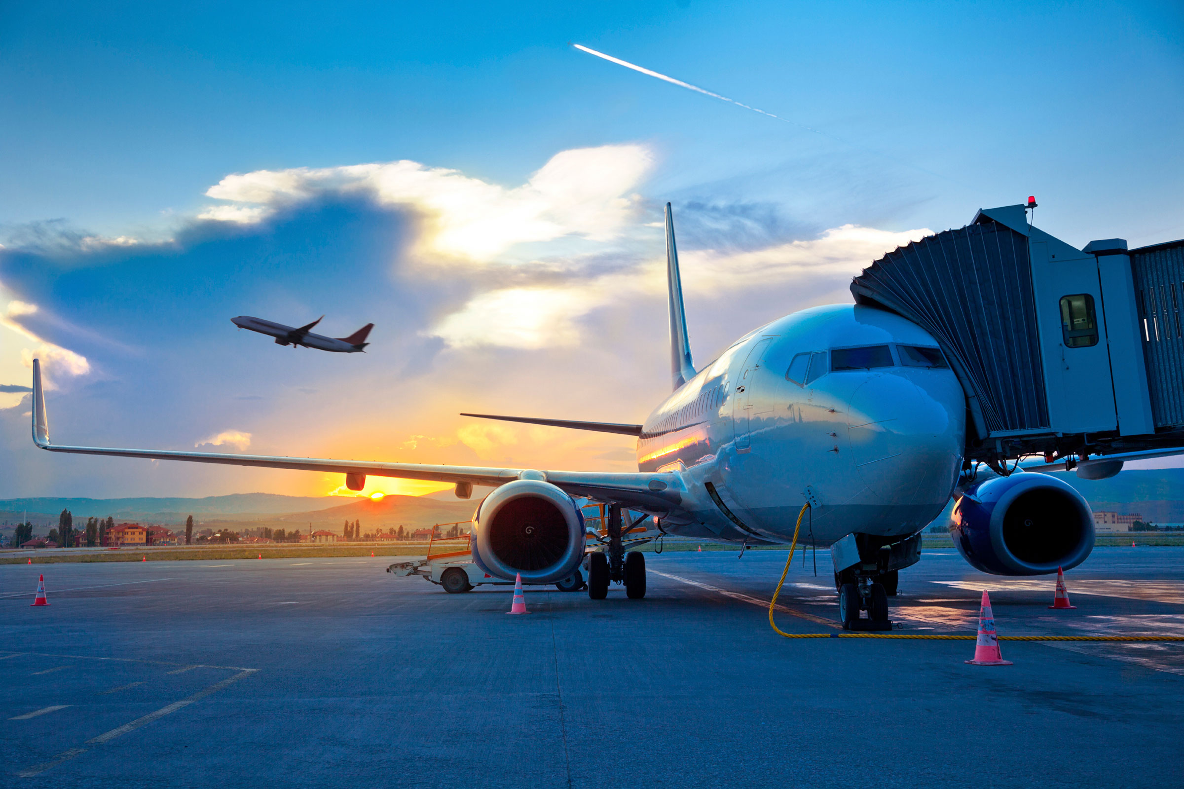 Airplane at sunset with jet bridge and another plane taking off HD Wallpaper
