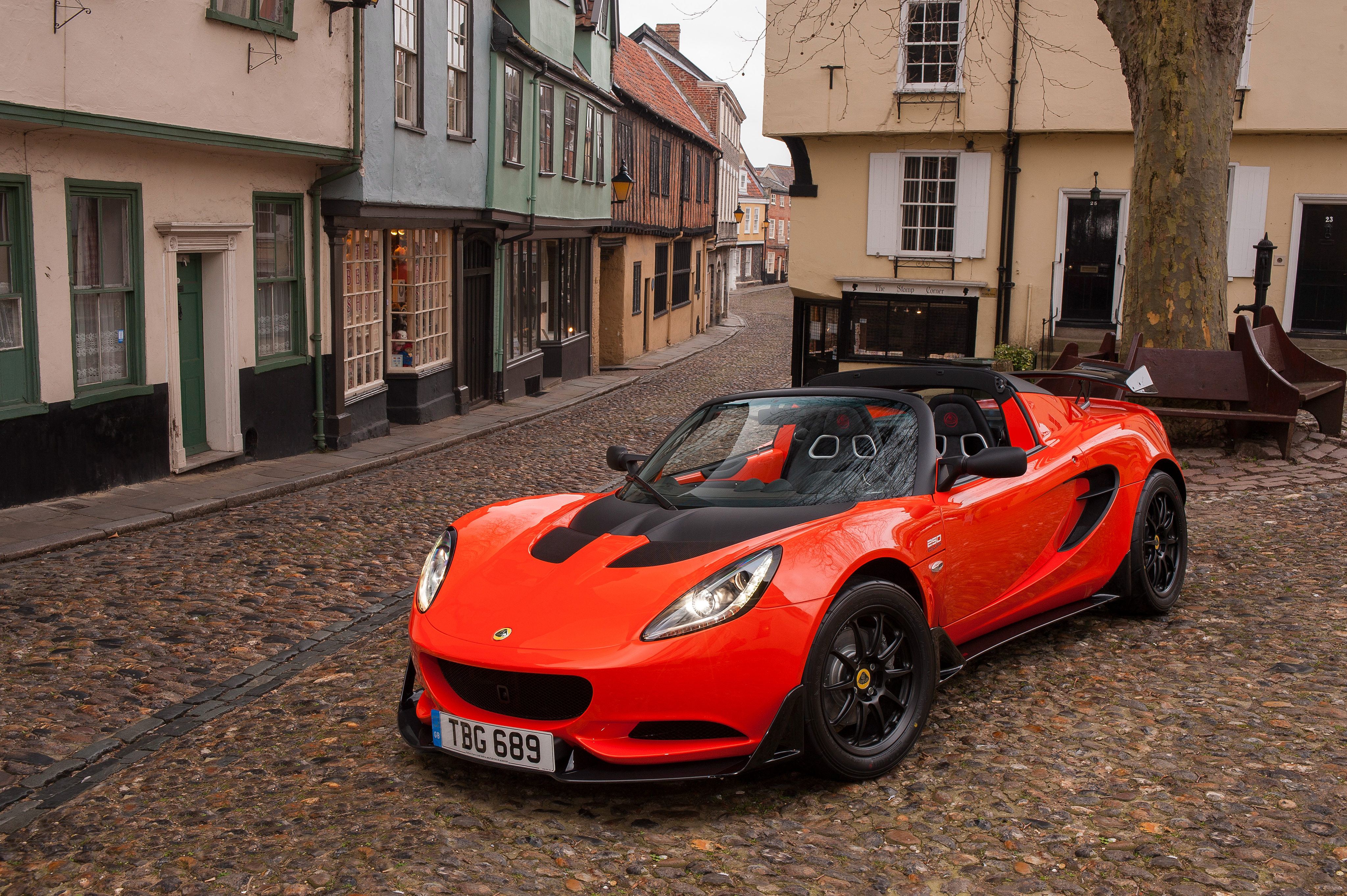 Orange Lotus Elise parked on cobblestone street HD Wallpaper