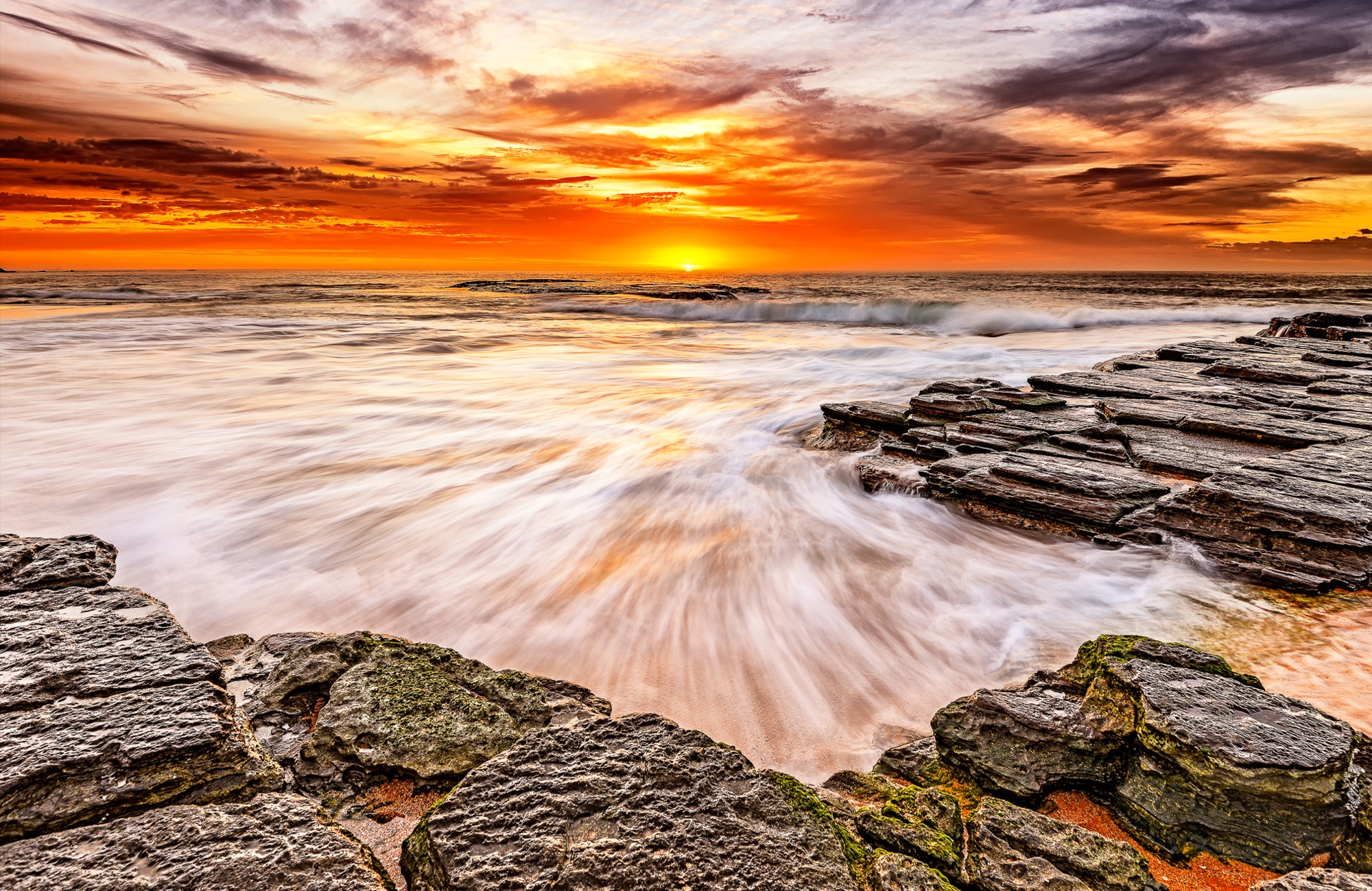 Sunset over the ocean with rocks and waves HD Wallpaper