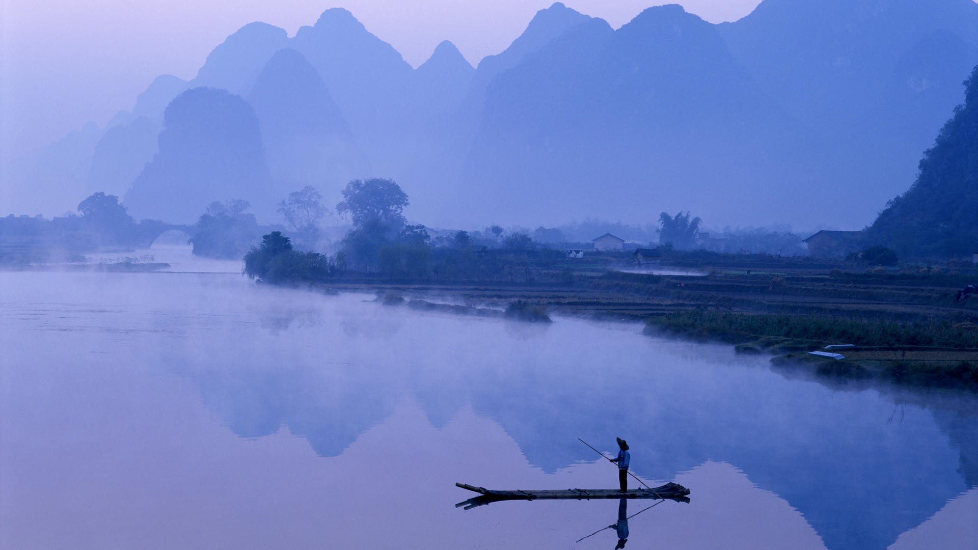 Fisherman on a raft on a misty river with karst mountains HD Wallpaper