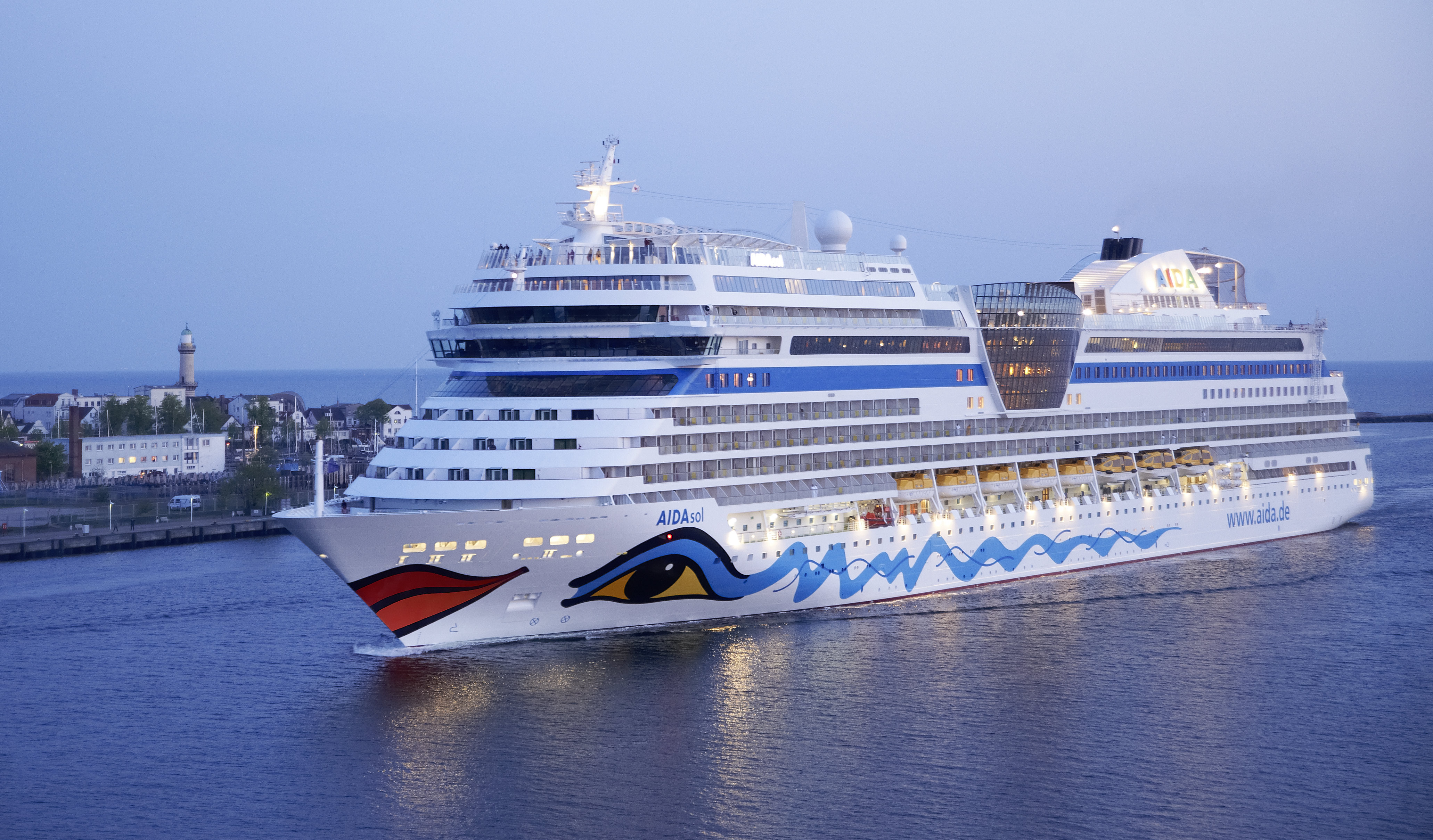 AIDAsol cruise ship sailing near a lighthouse and town HD Wallpaper