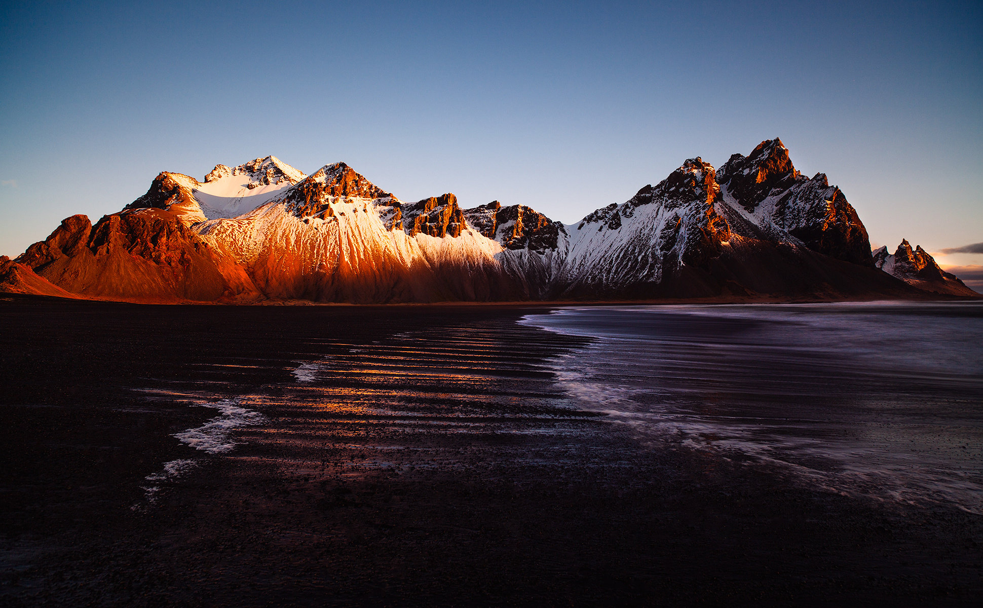 Snow-capped mountains on a black sand beach in Iceland HD Wallpaper