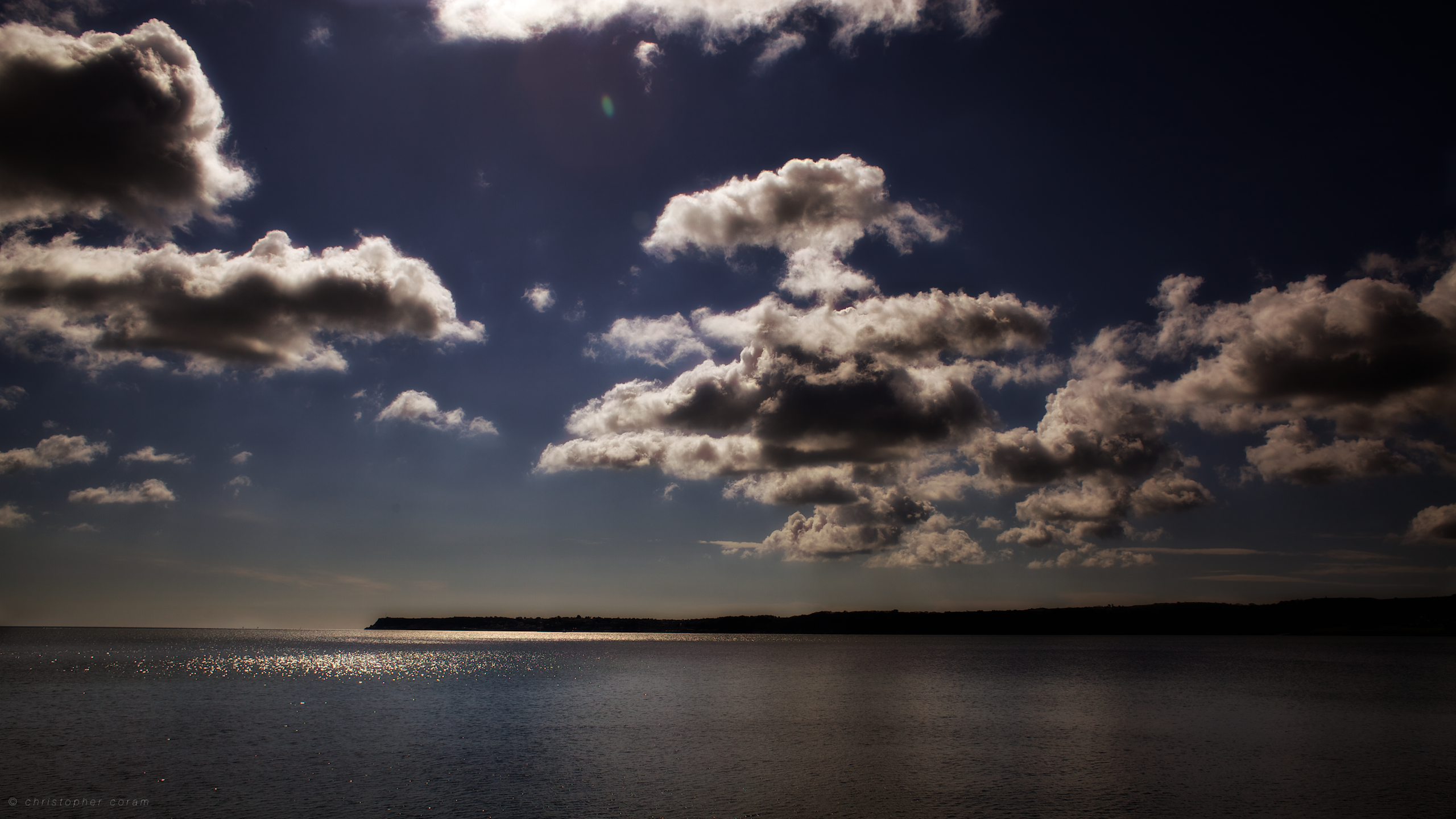 Clouds over the sea with a distant shore HD Wallpaper