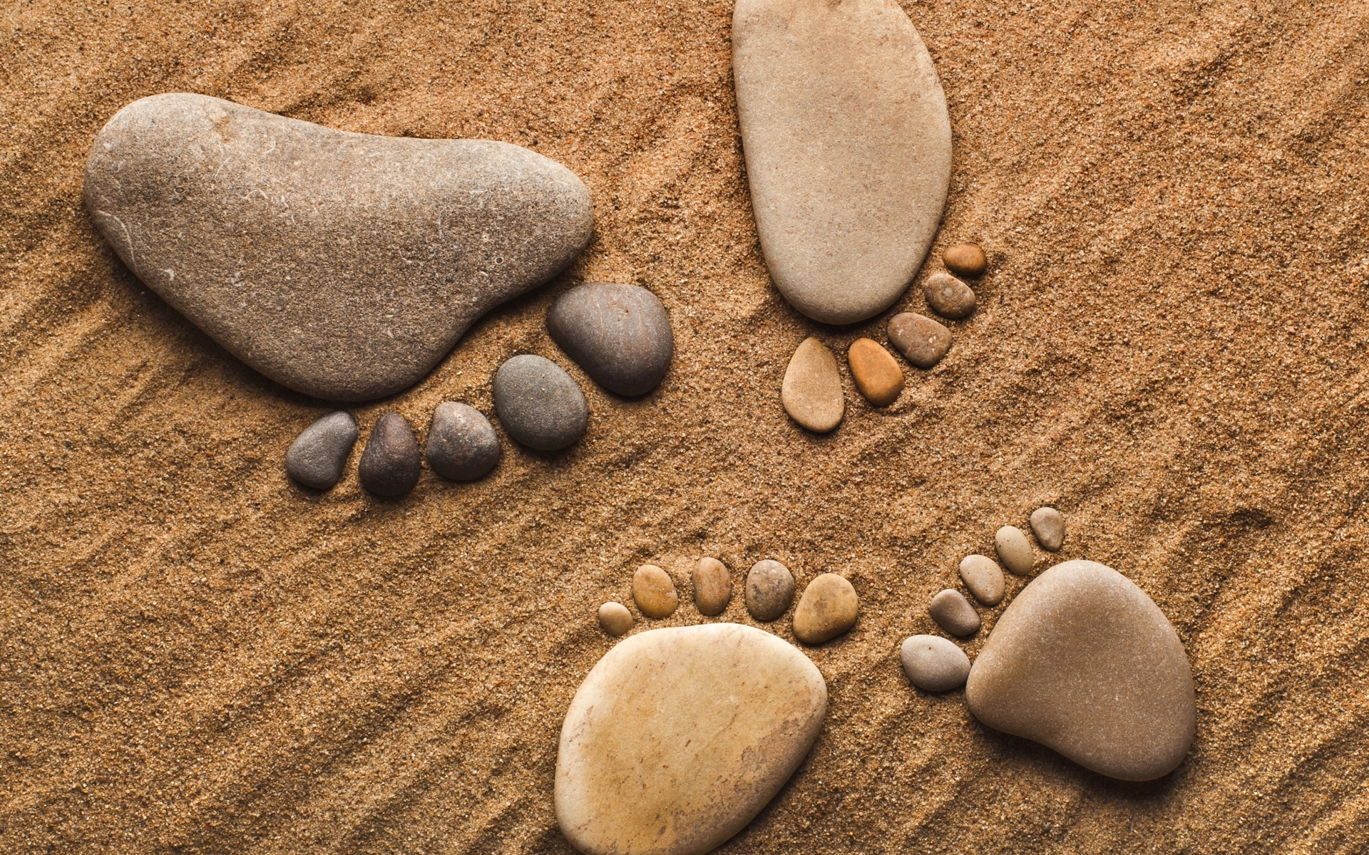 Footprints made of stones on sand HD Wallpaper
