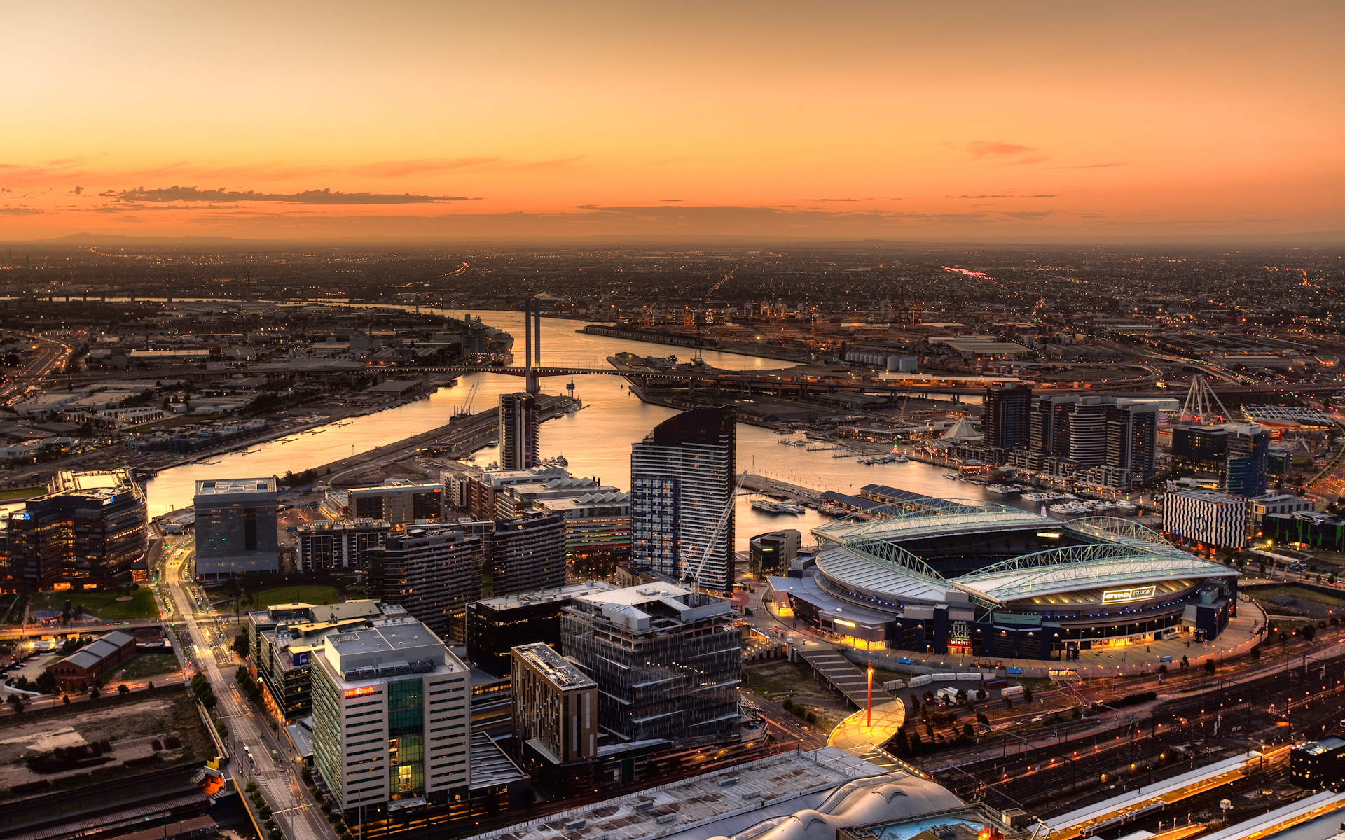 Cityscape at sunset with stadium and river HD Wallpaper