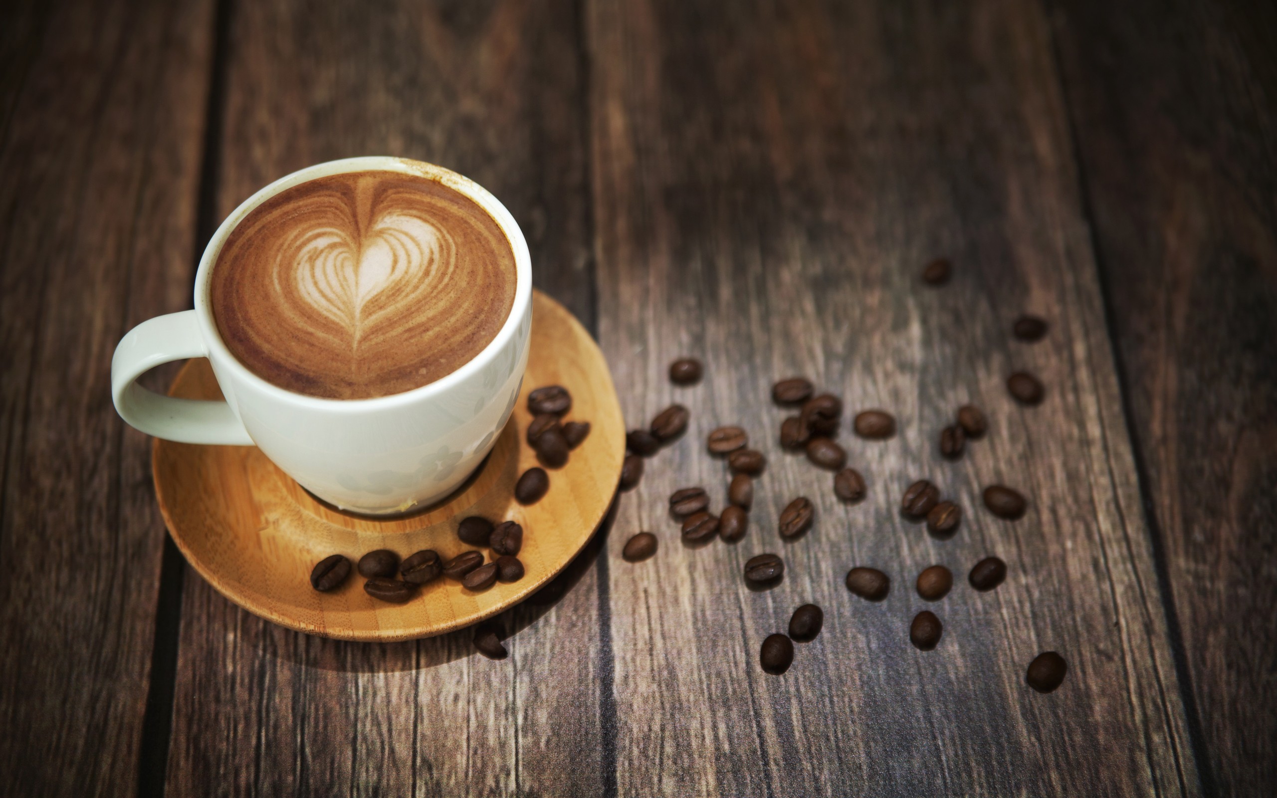 Latte art coffee cup with beans on wooden table HD Wallpaper