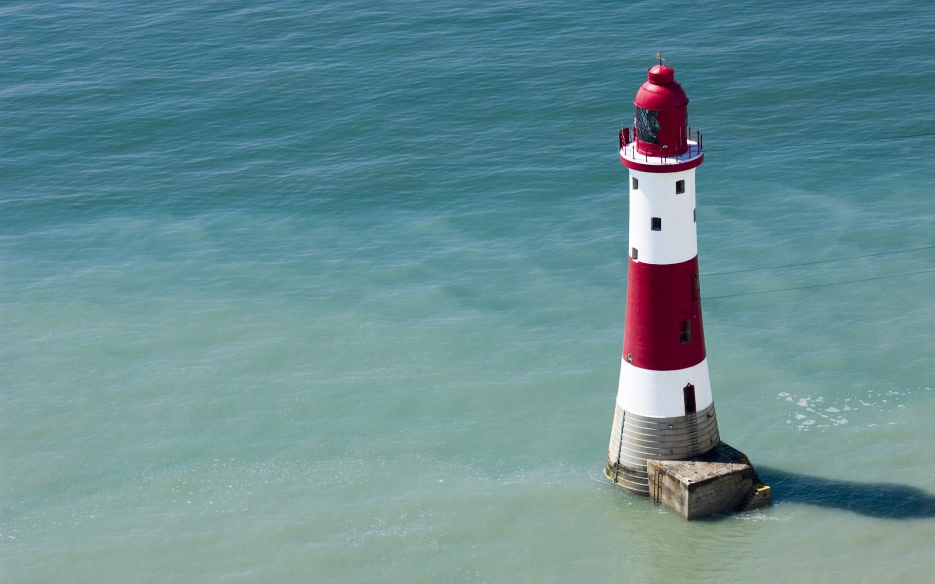 Red and white lighthouse in the ocean HD Wallpaper