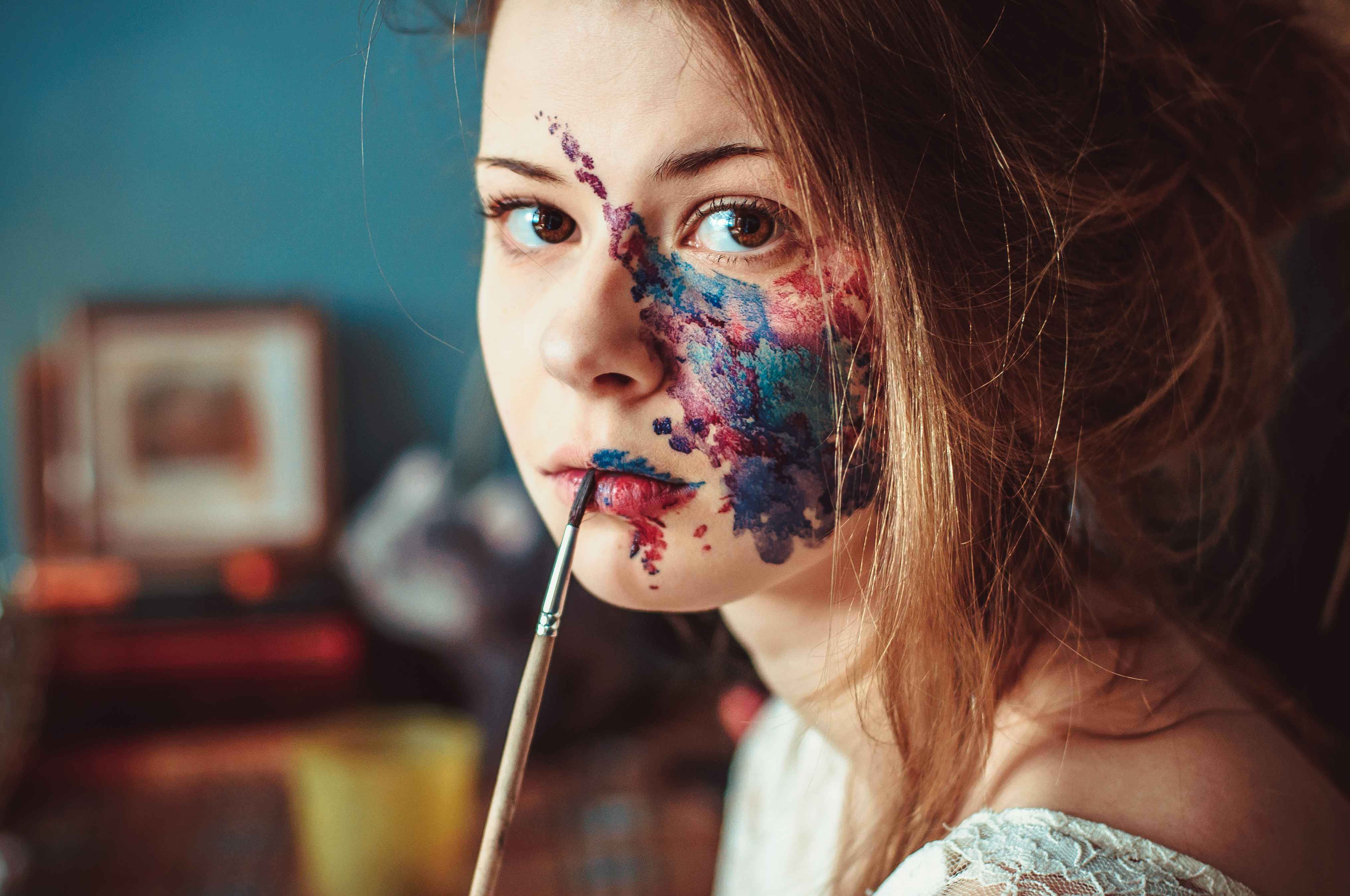 Woman with colorful paint on her face holding a paintbrush HD Wallpaper