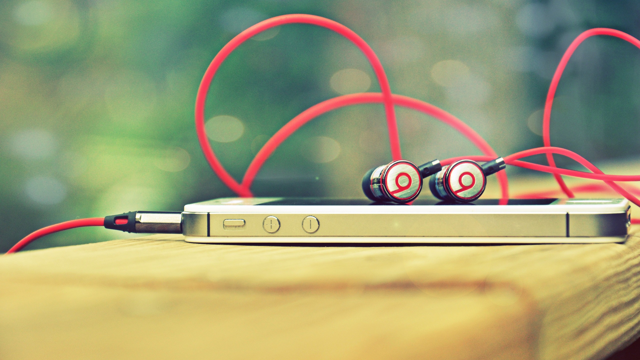 iPhone with red Beats headphones on wooden surface HD Wallpaper