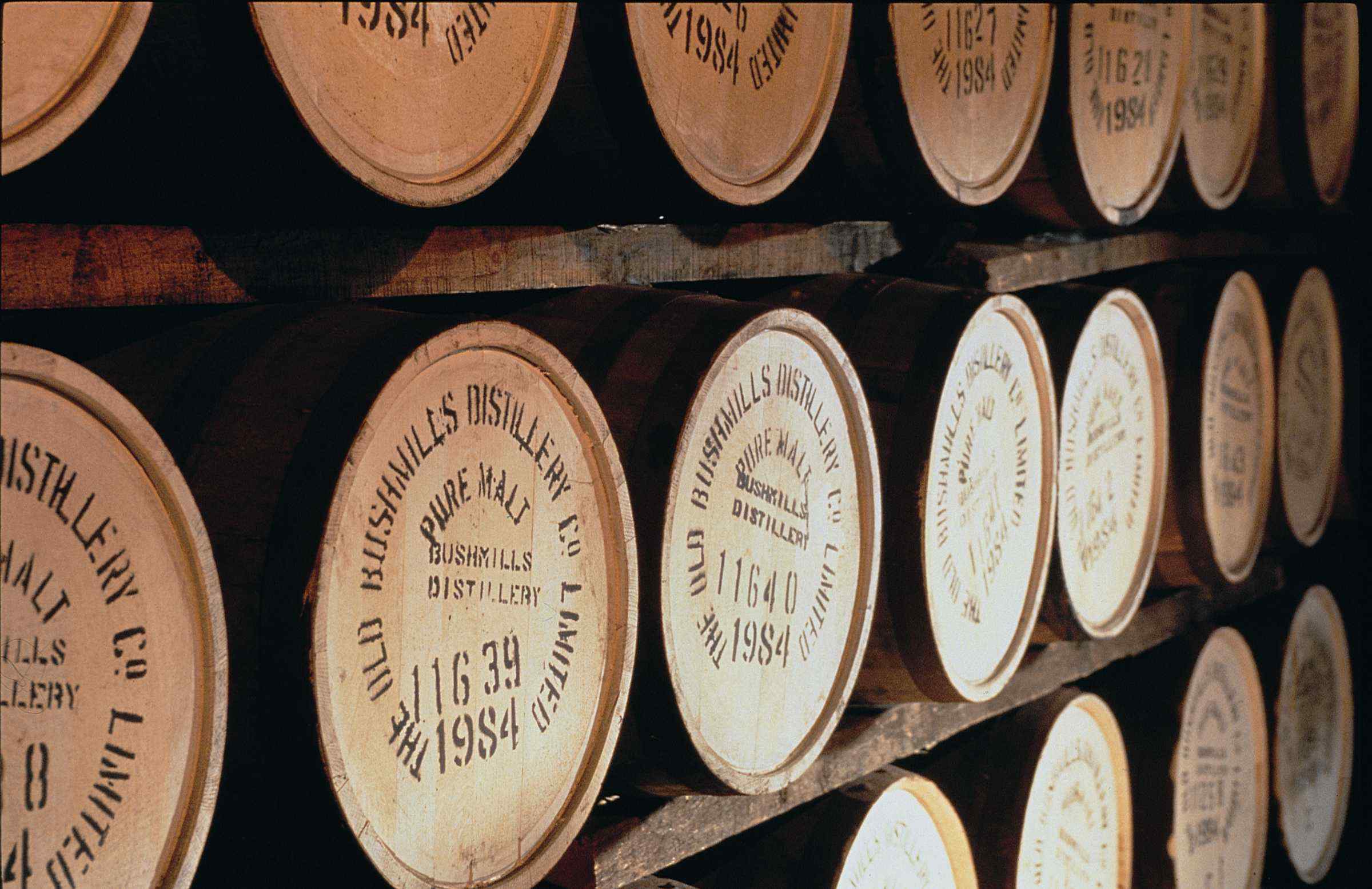 Bushmills Distillery whisky barrels stacked in storage HD Wallpaper