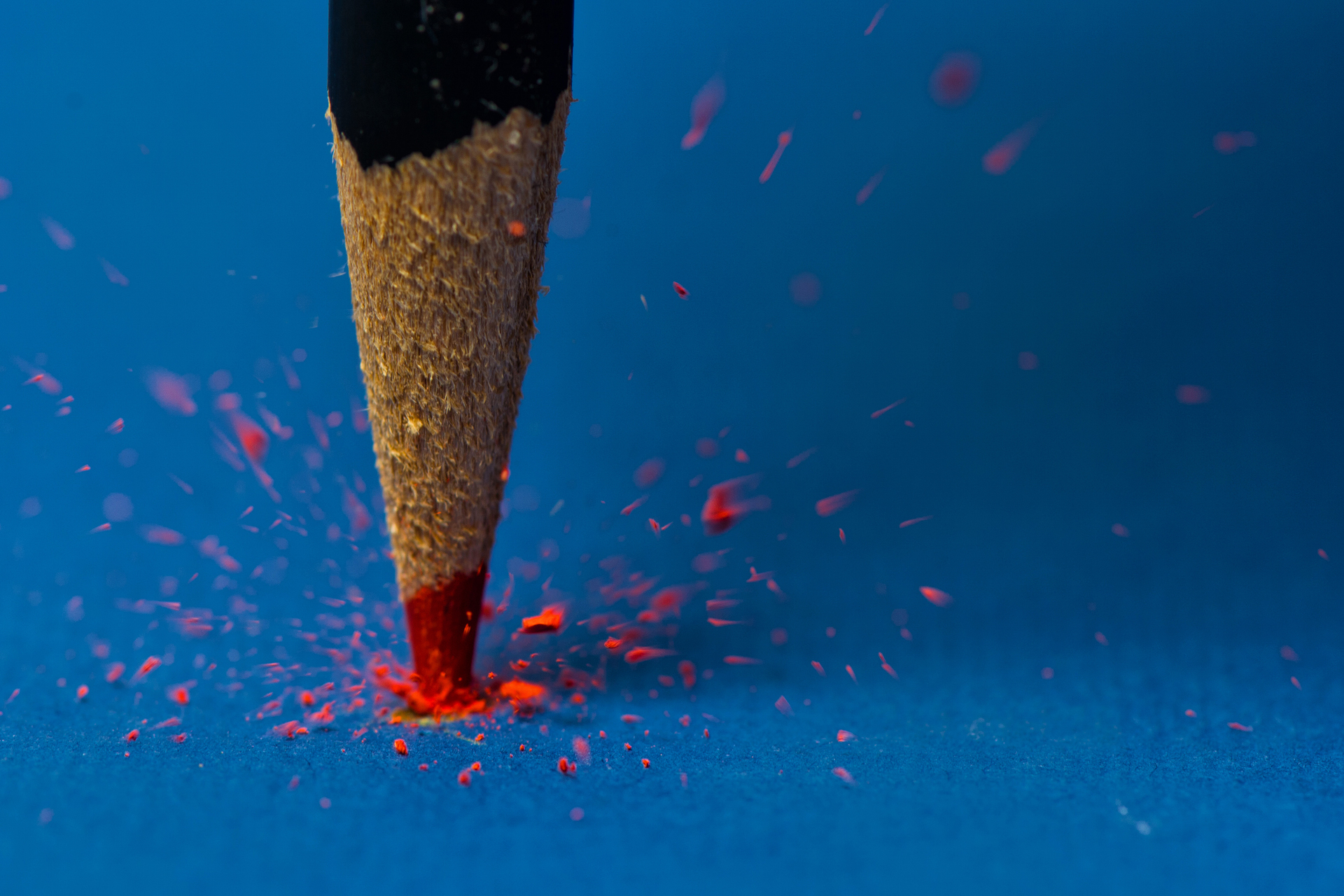 Close-up of a red pencil breaking on a blue surface HD Wallpaper