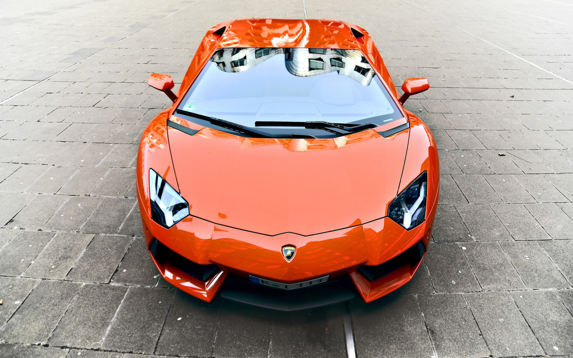 Orange Lamborghini Aventador parked on stone pavement HD Wallpaper