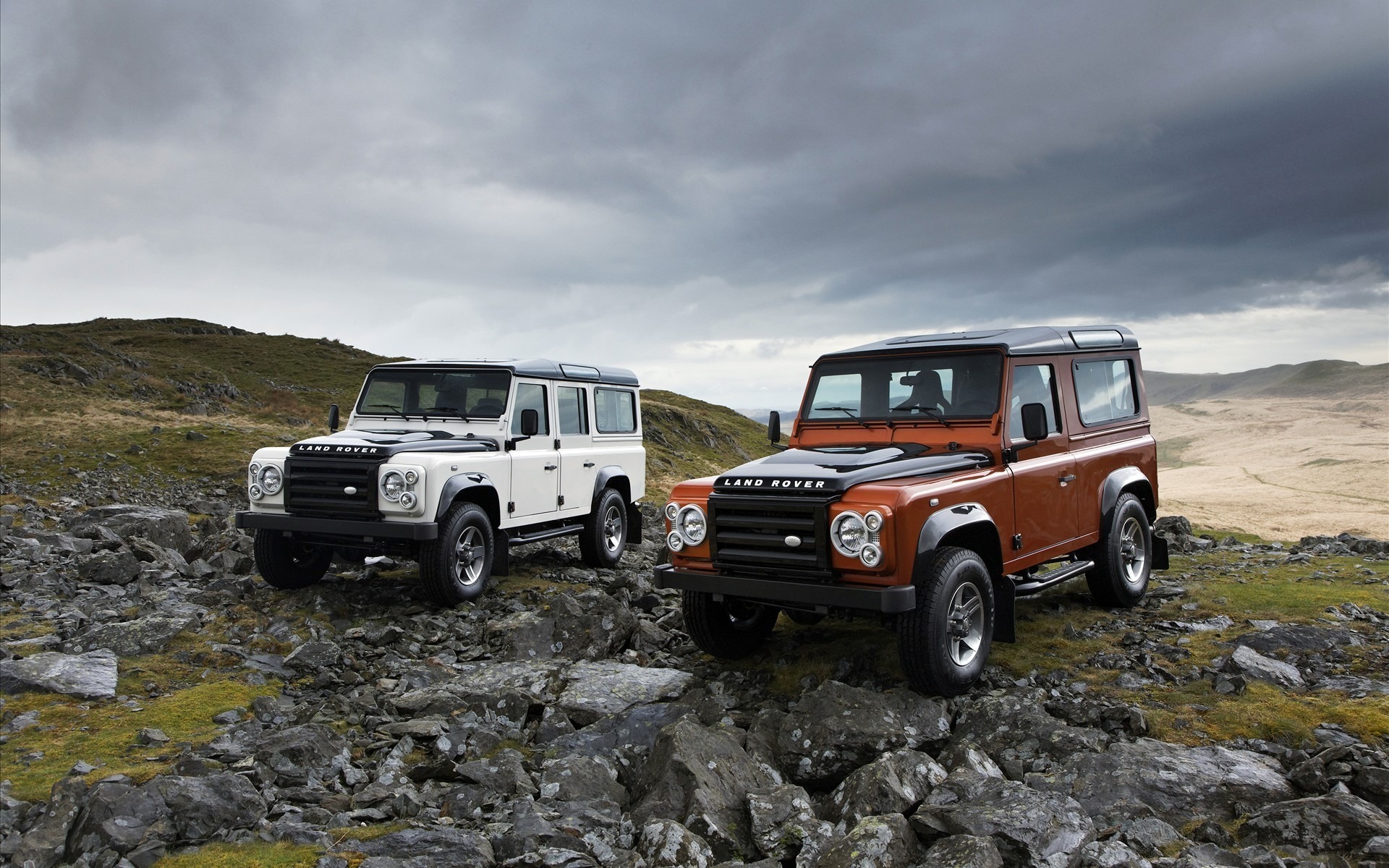 Two Land Rover Defenders on rocky terrain HD Wallpaper