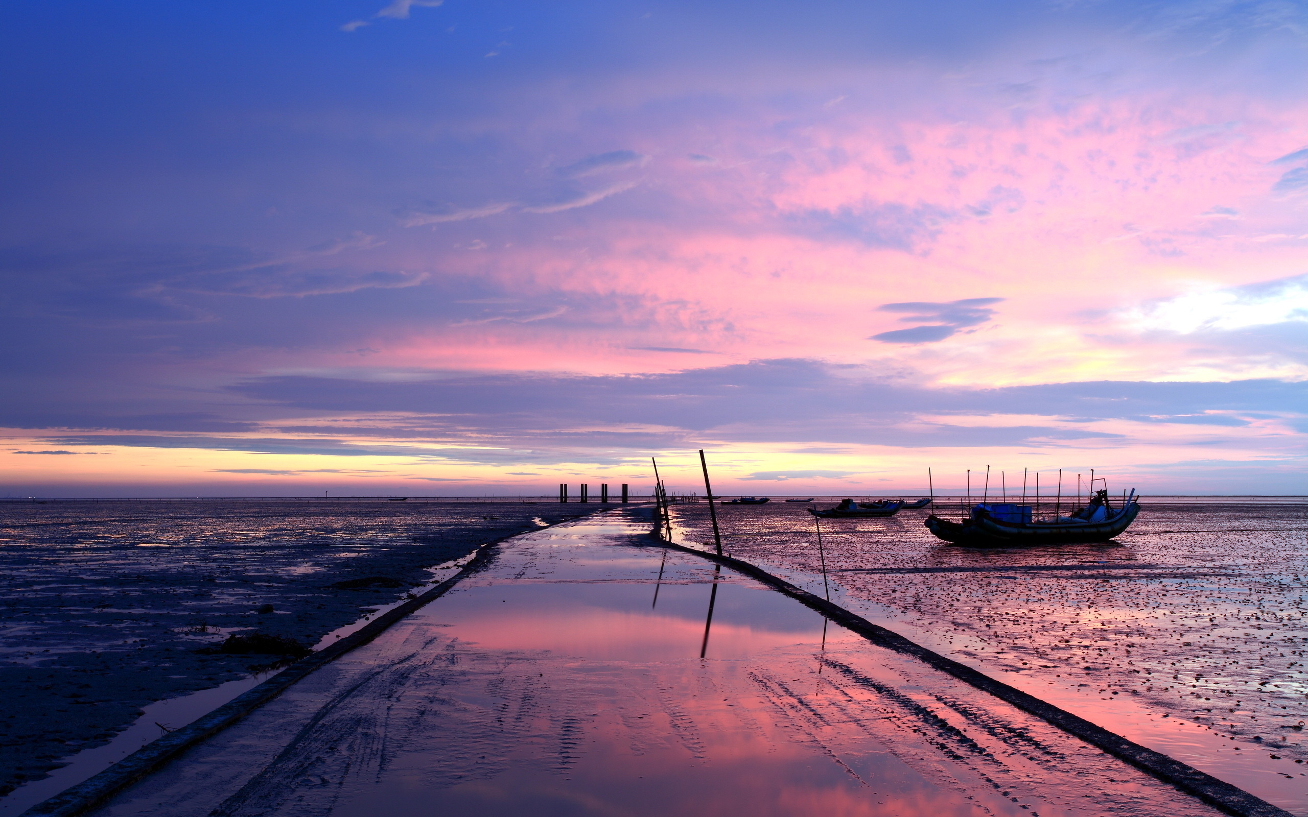 Sunset over a muddy shore with boats HD Wallpaper