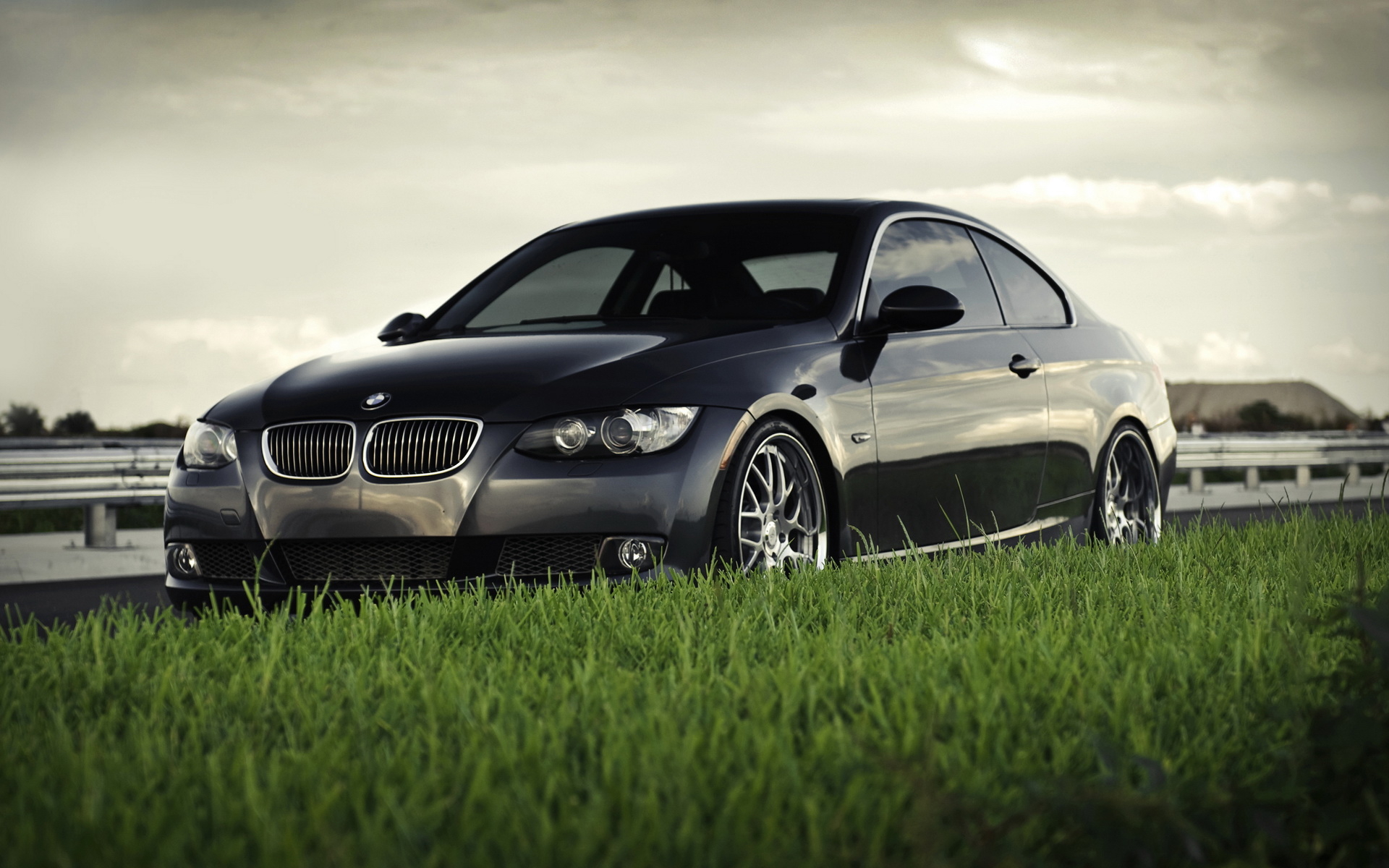 Black BMW coupe on grassy roadside HD Wallpaper