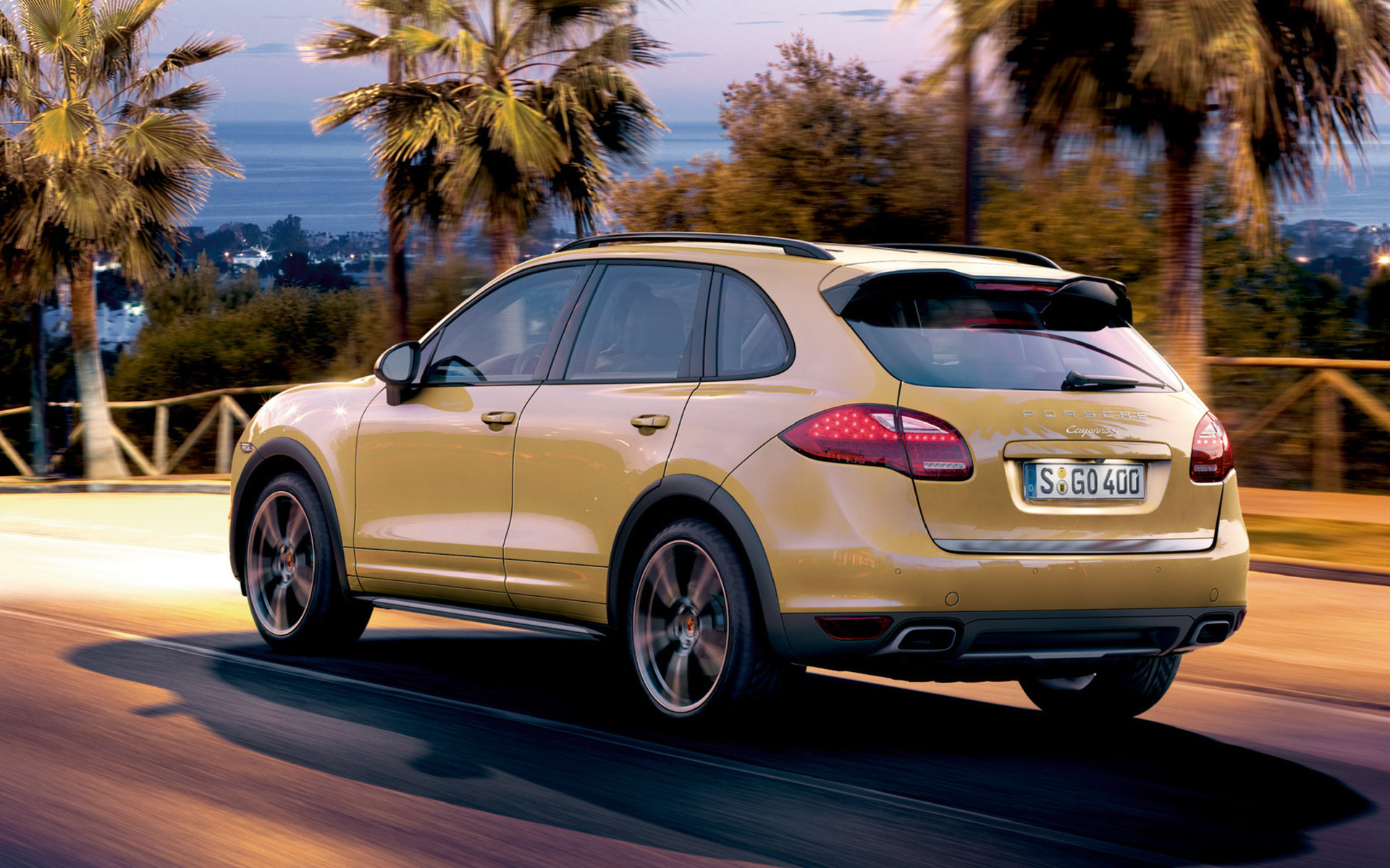 Yellow Porsche Cayenne driving on a road at dusk HD Wallpaper