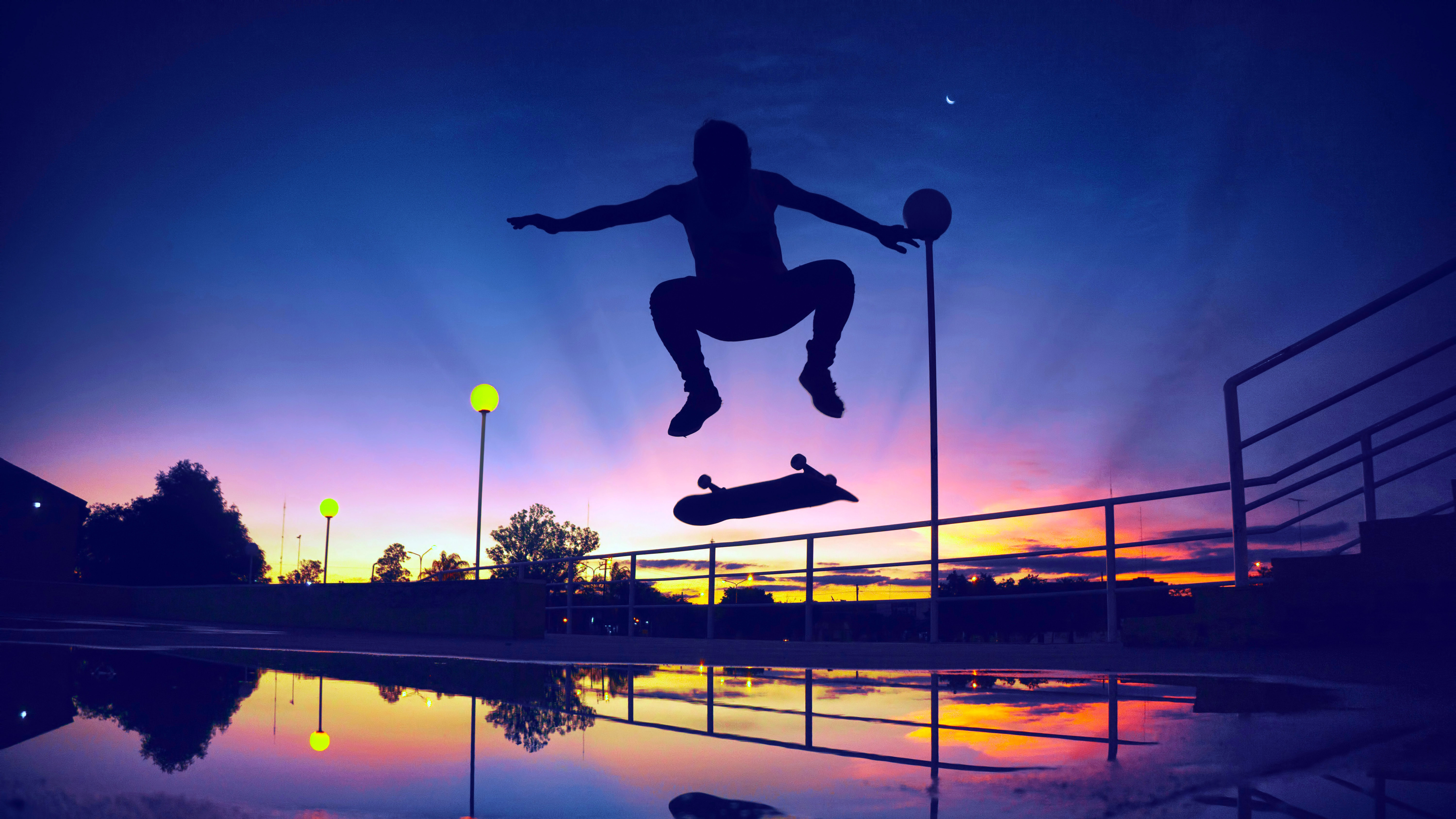Silhouette of a skateboarder jumping at sunset with reflections HD Wallpaper