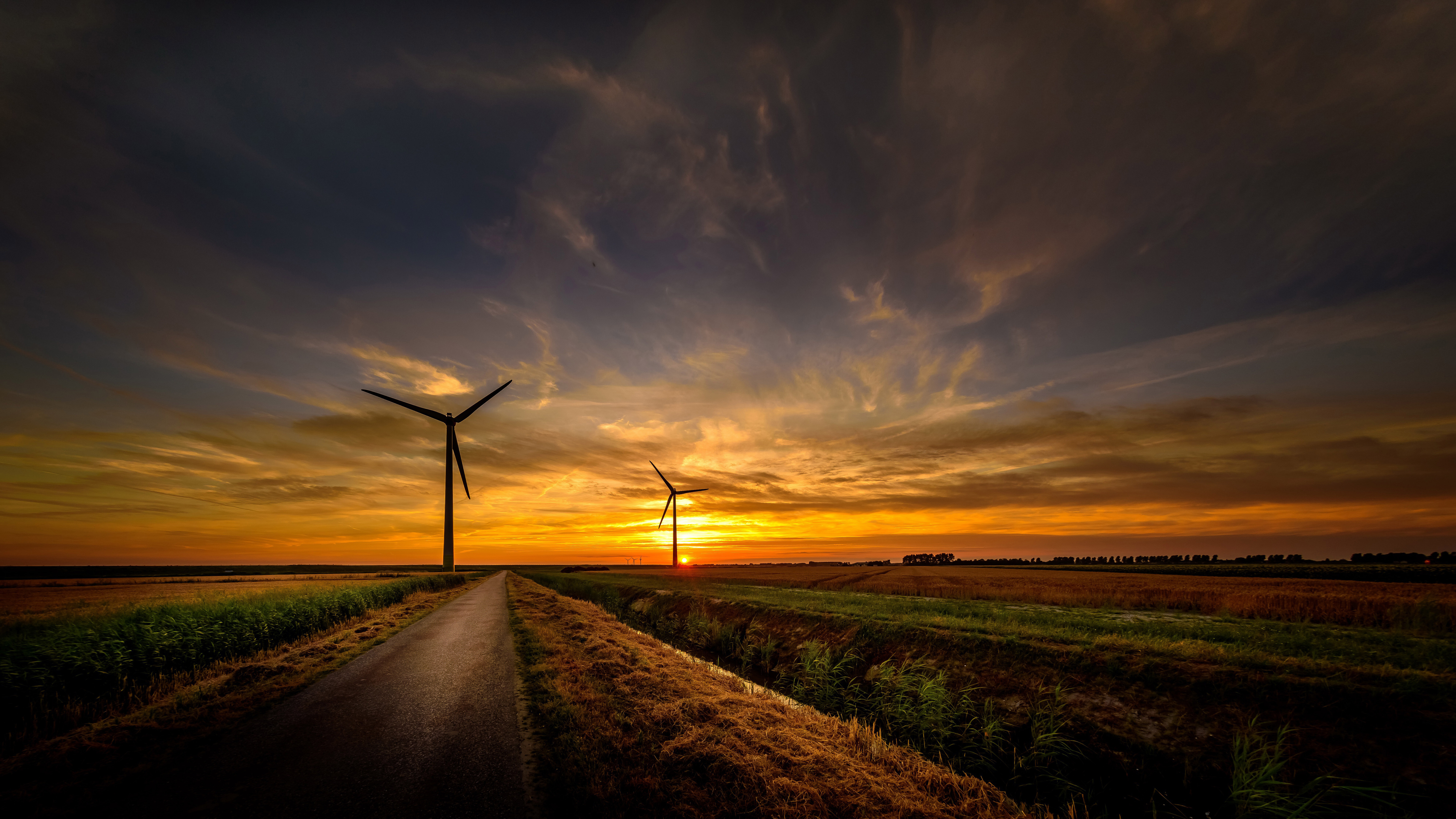 Wind turbines at sunset on a rural road HD Wallpaper