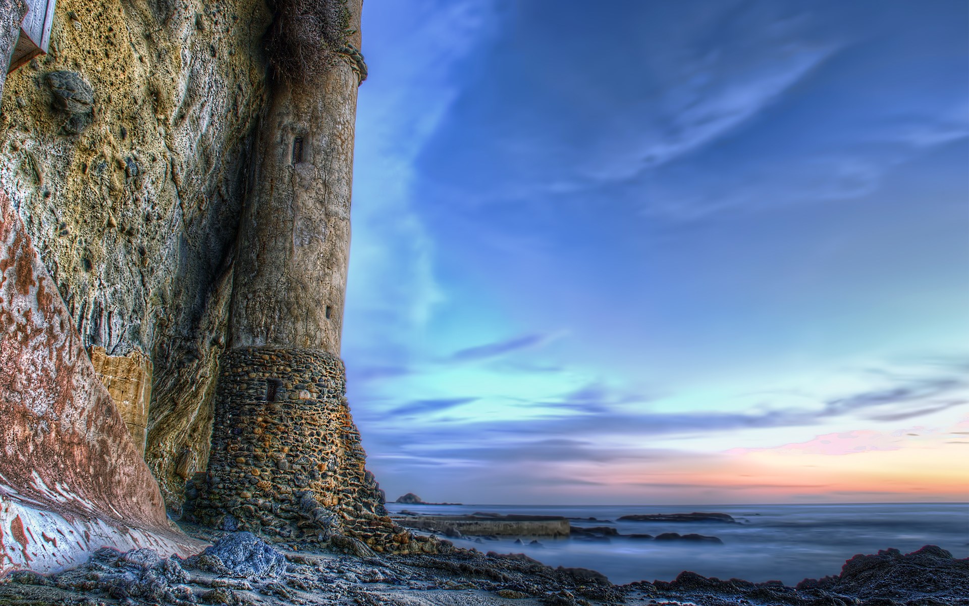 Stone tower on a rocky coast at sunset HD Wallpaper