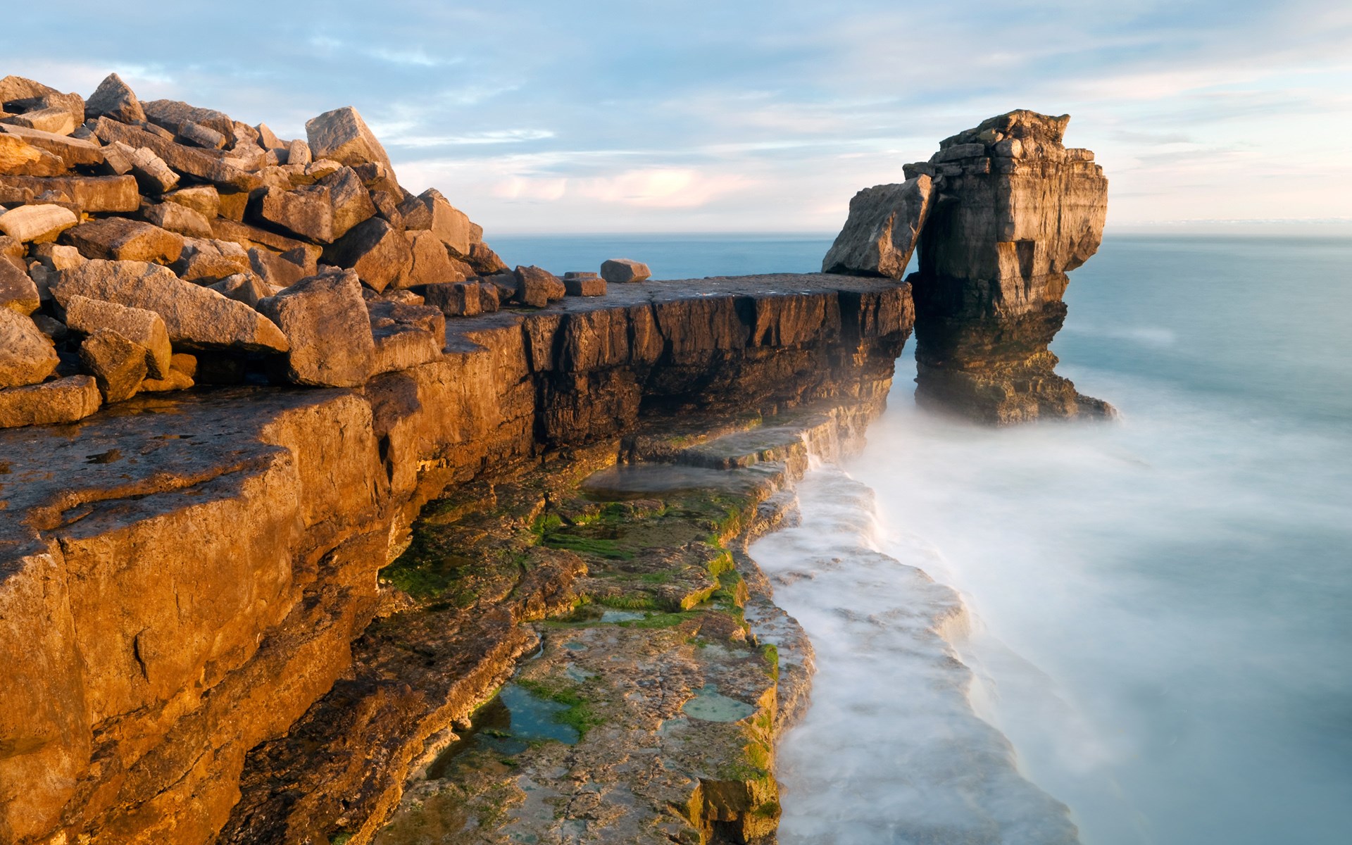 Rocky coastline with waves crashing at sunset HD Wallpaper