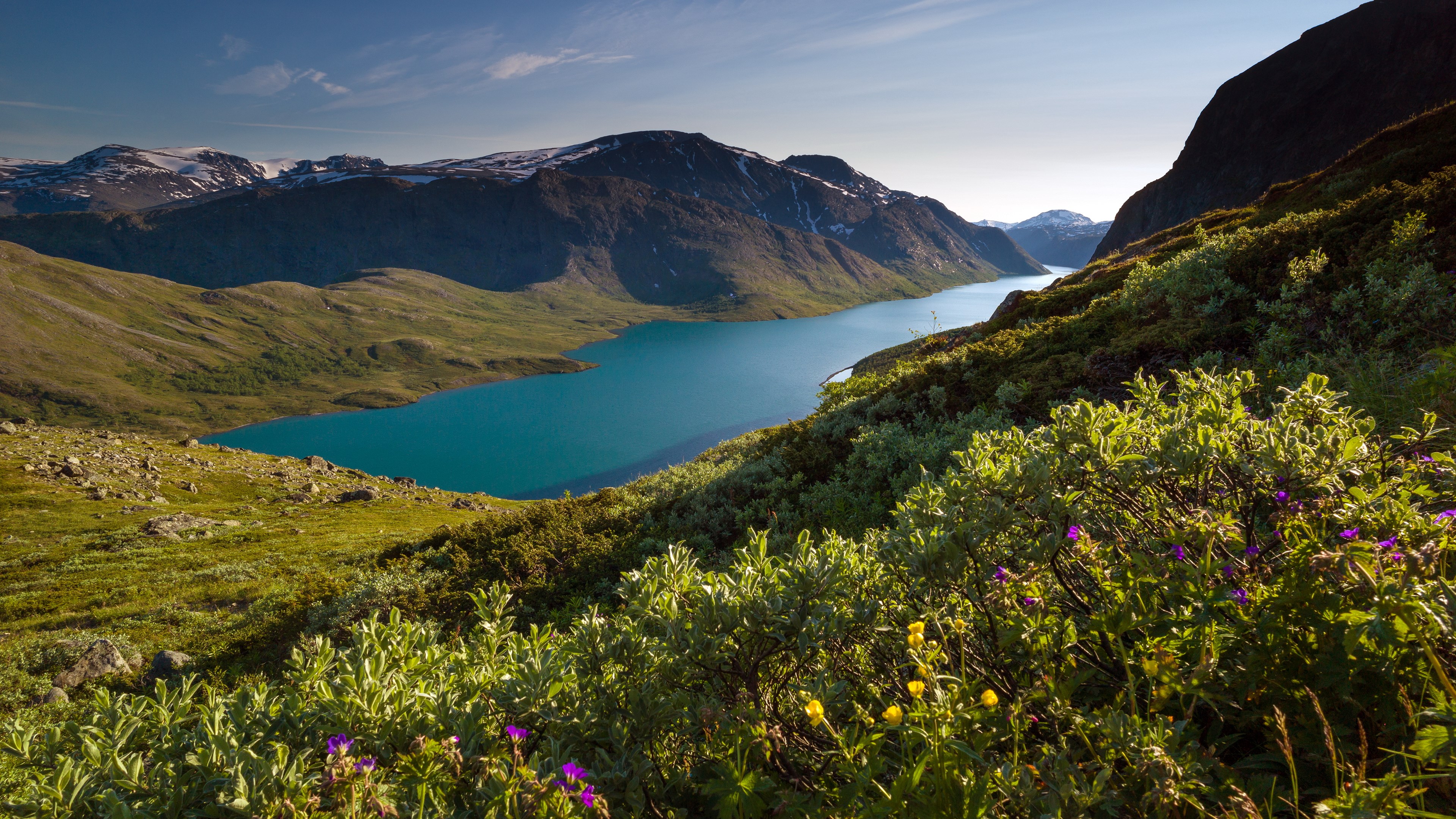 Turquoise lake surrounded by mountains and green hills HD Wallpaper