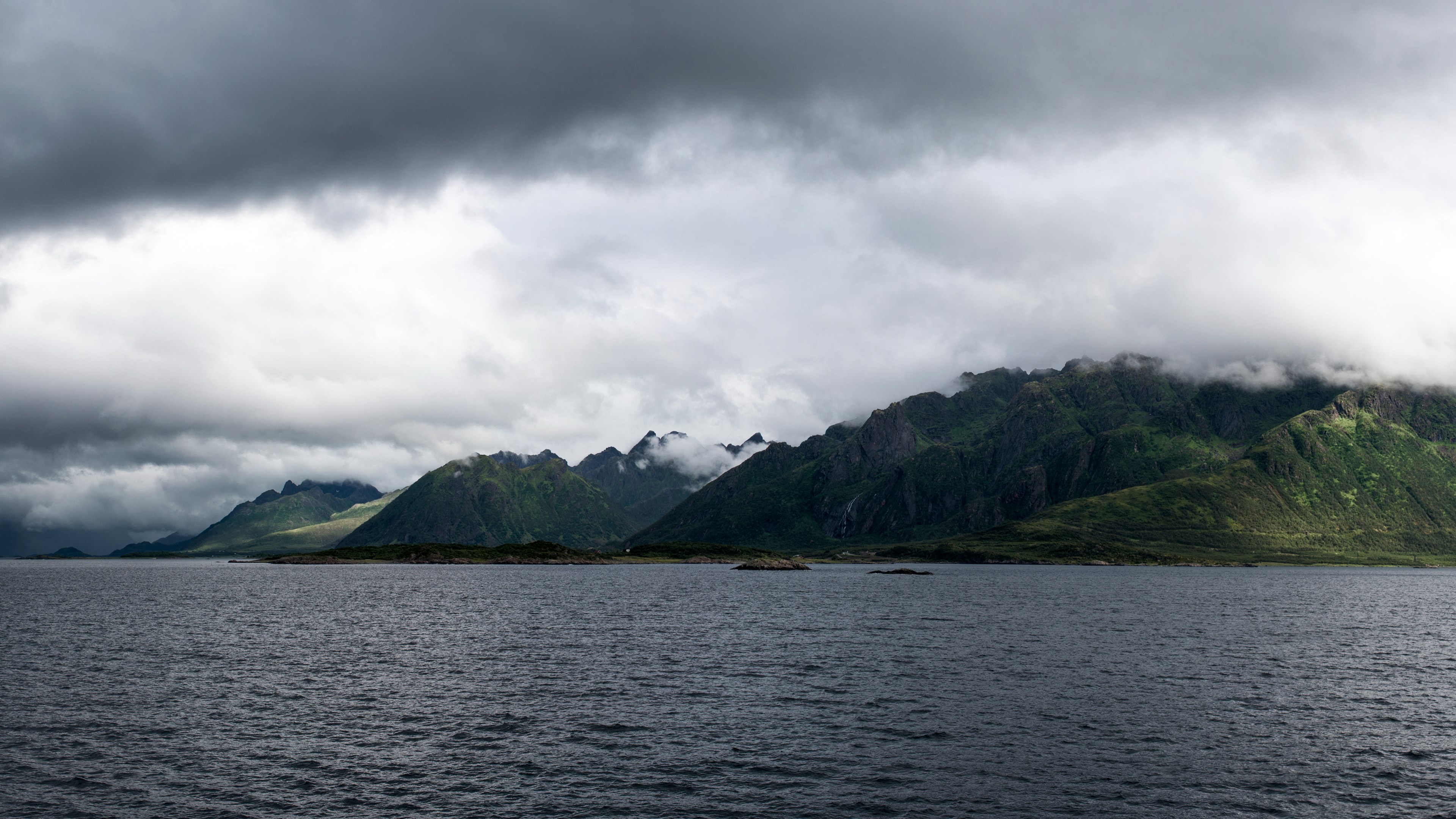 Dark clouds over a Norwegian fjord with mountains HD Wallpaper