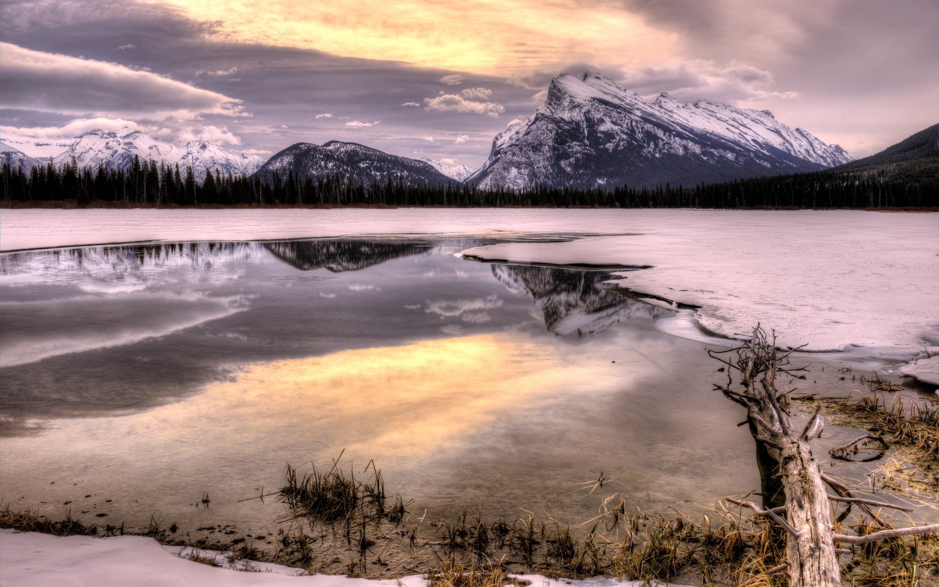 Frozen lake reflecting snow-capped mountains and cloudy sky HD Wallpaper