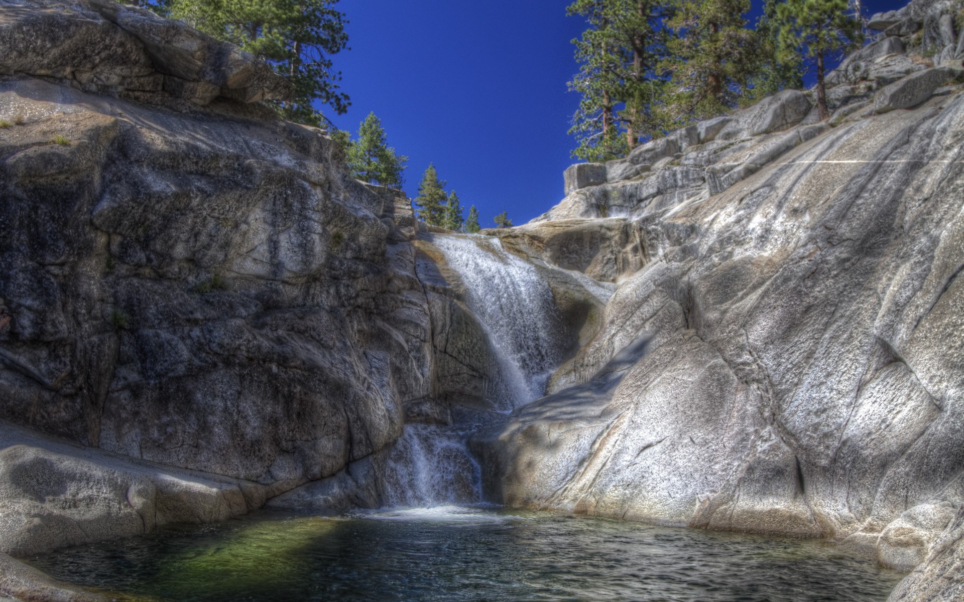 Waterfall cascading over rocks into a pool HD Wallpaper