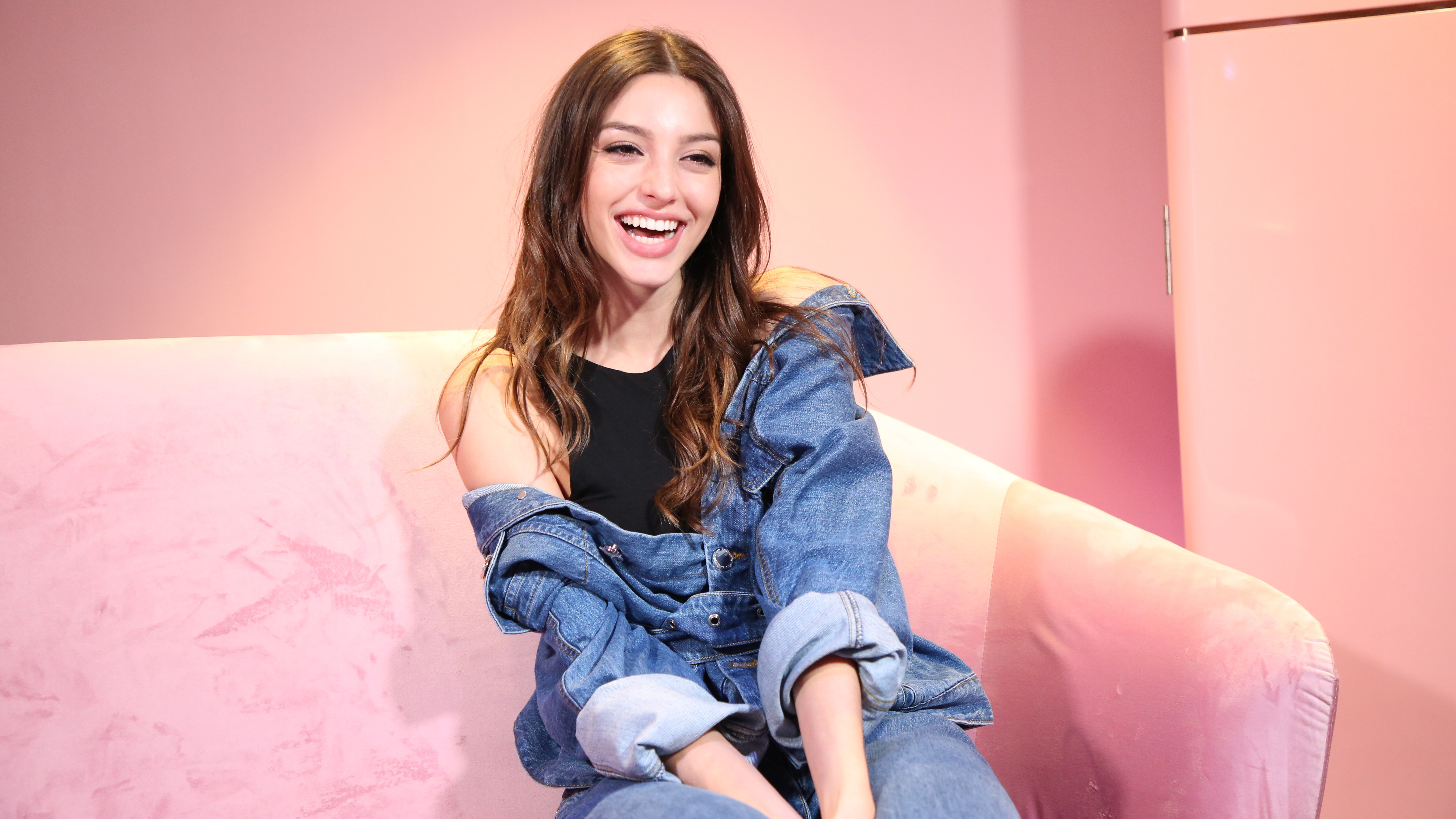 Woman in denim jacket sitting on pink couch HD Wallpaper