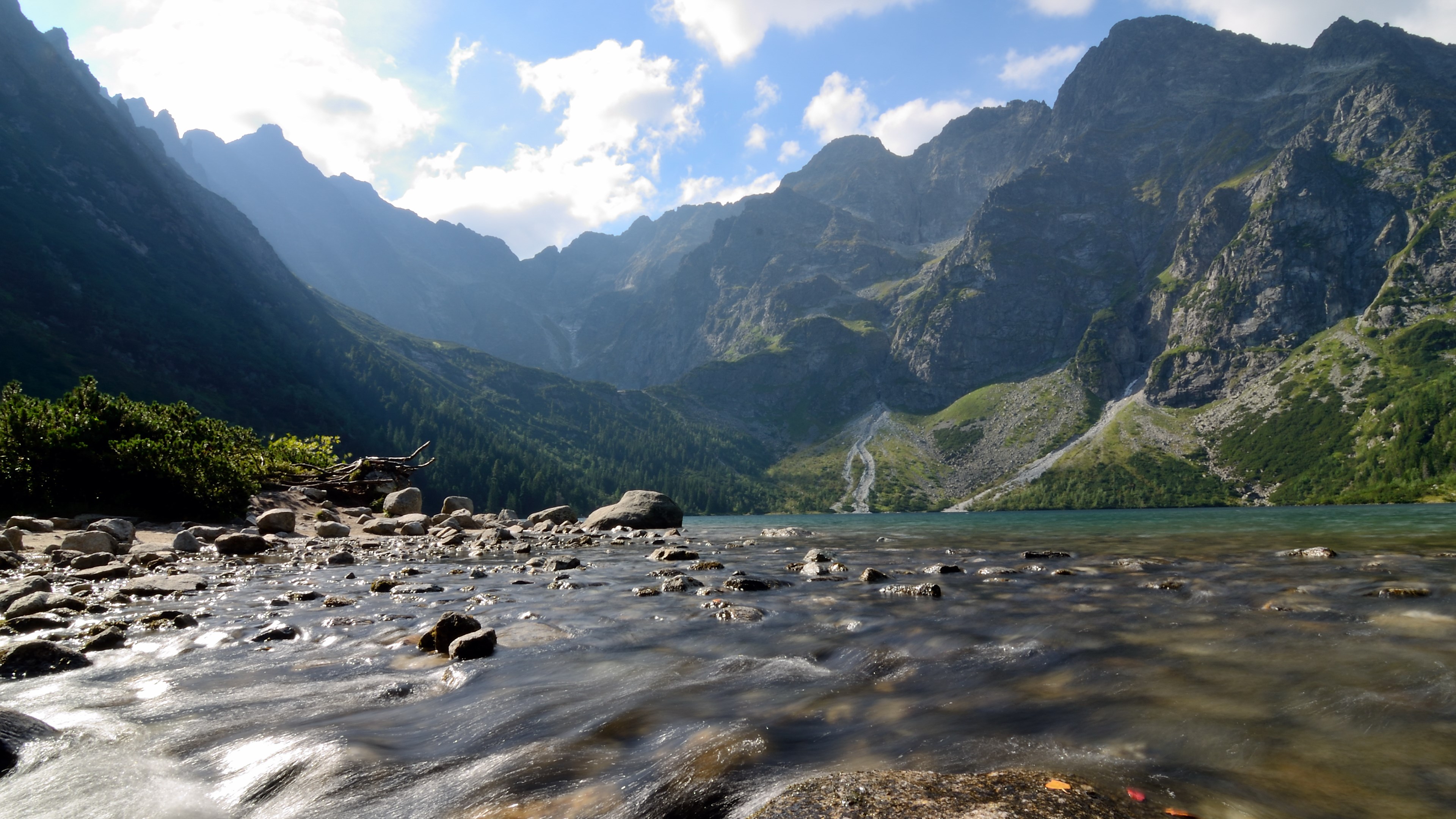 Mountain lake with rocky shore and flowing water HD Wallpaper