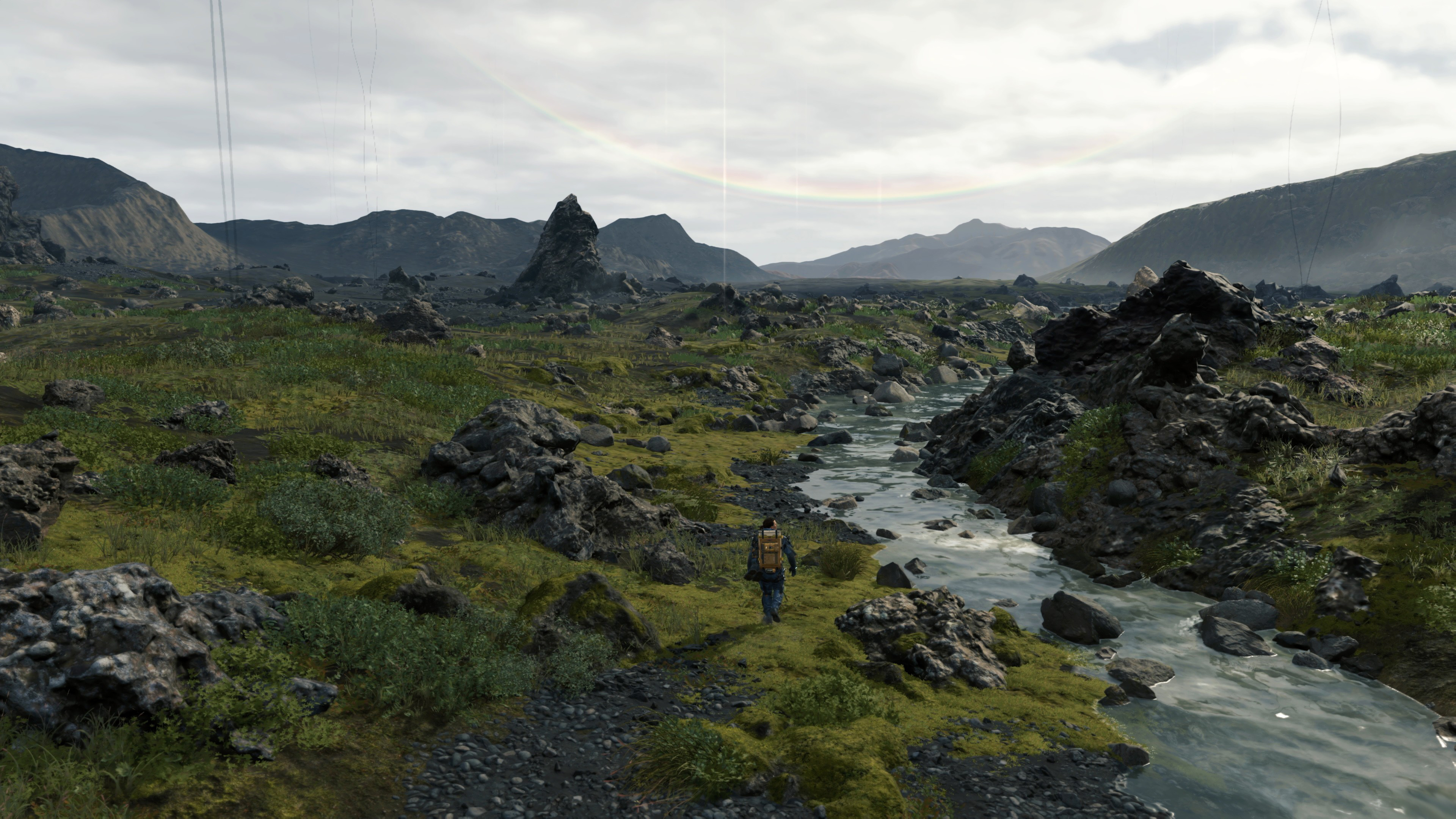 Man walking through rocky landscape in Death Stranding 4K HD Wallpaper