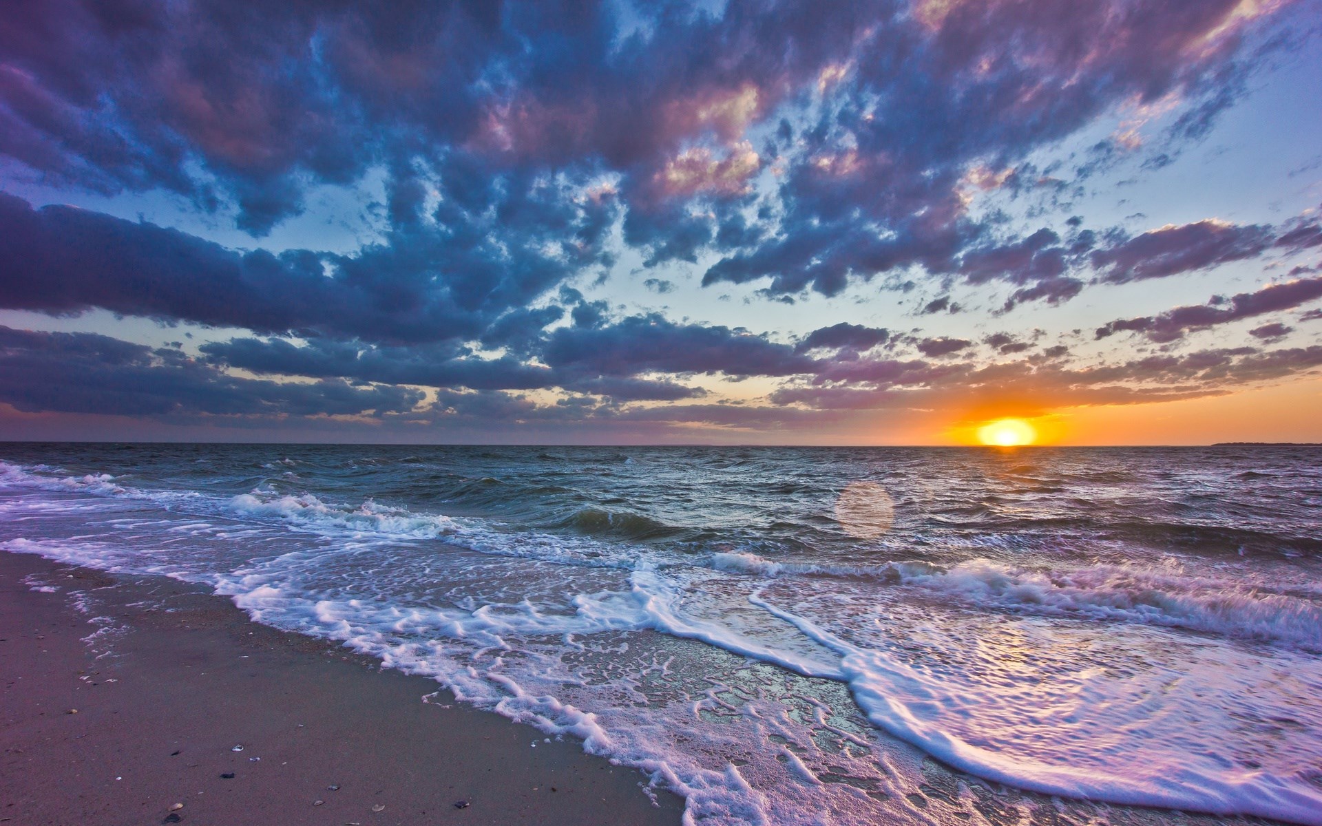 Sunset over the ocean with waves crashing on the shore HD Wallpaper