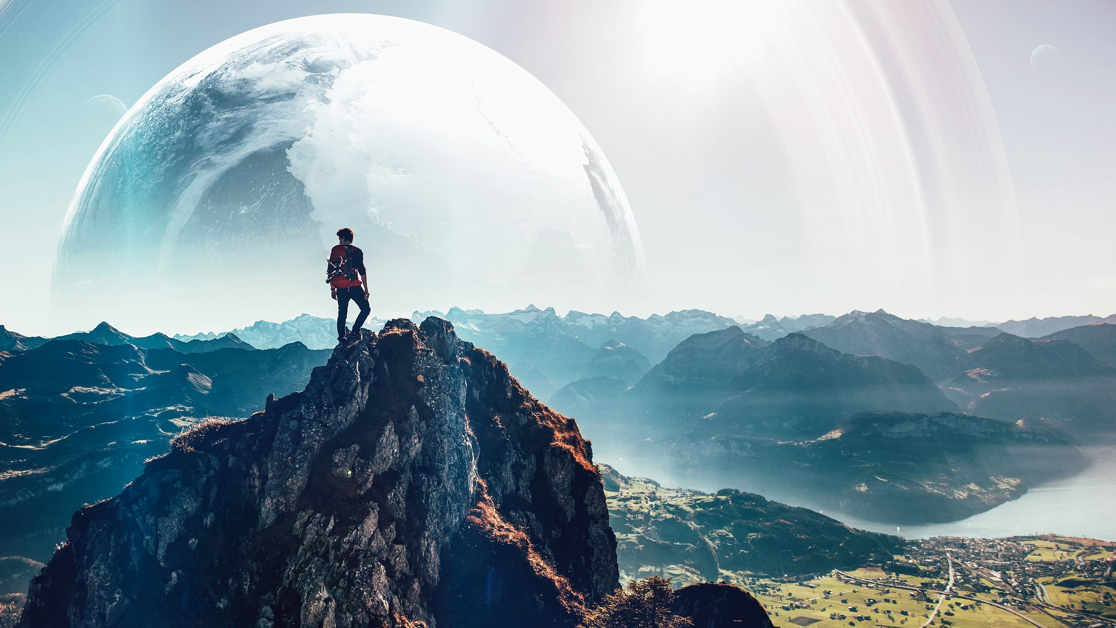 Man on mountain peak with planet and rings in sky HD Wallpaper