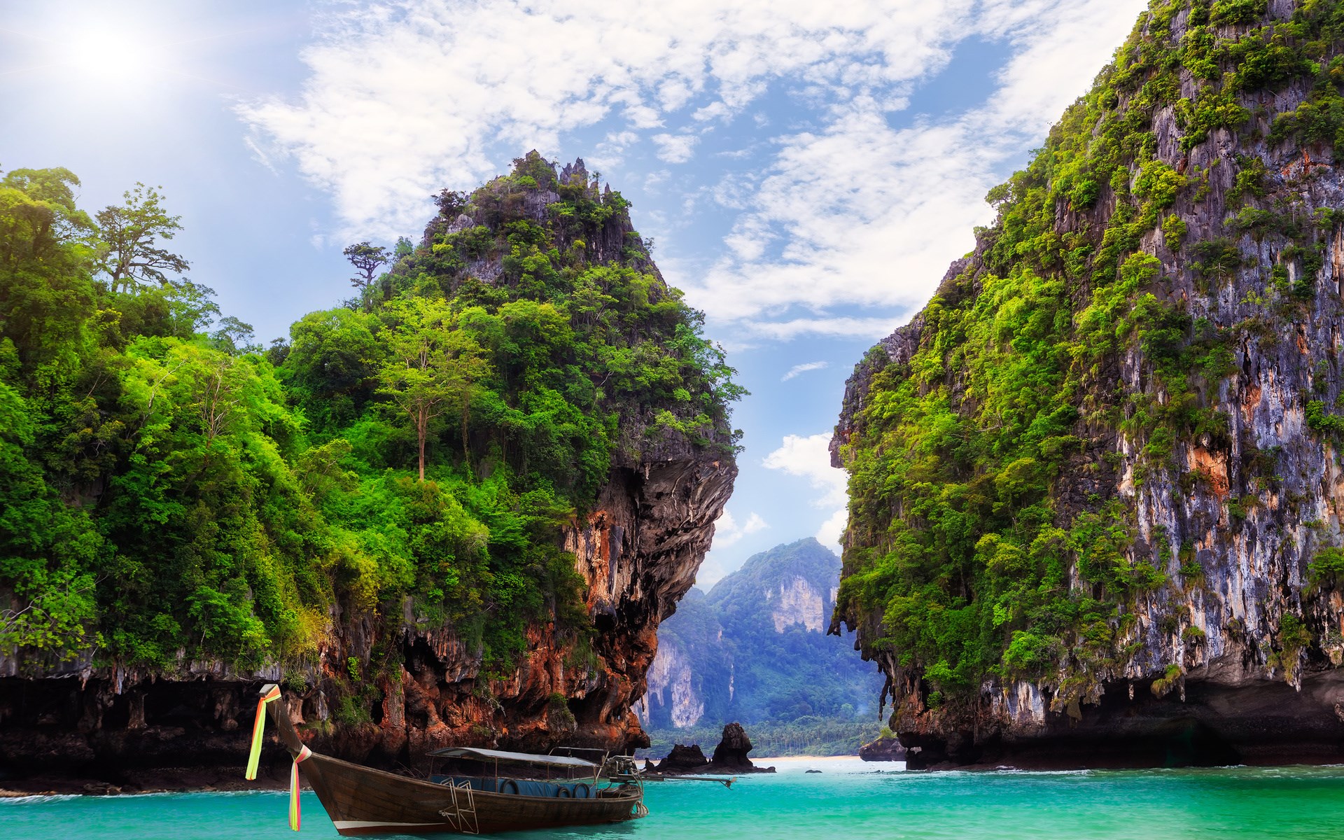 Longtail boat in a tropical bay between limestone cliffs HD Wallpaper