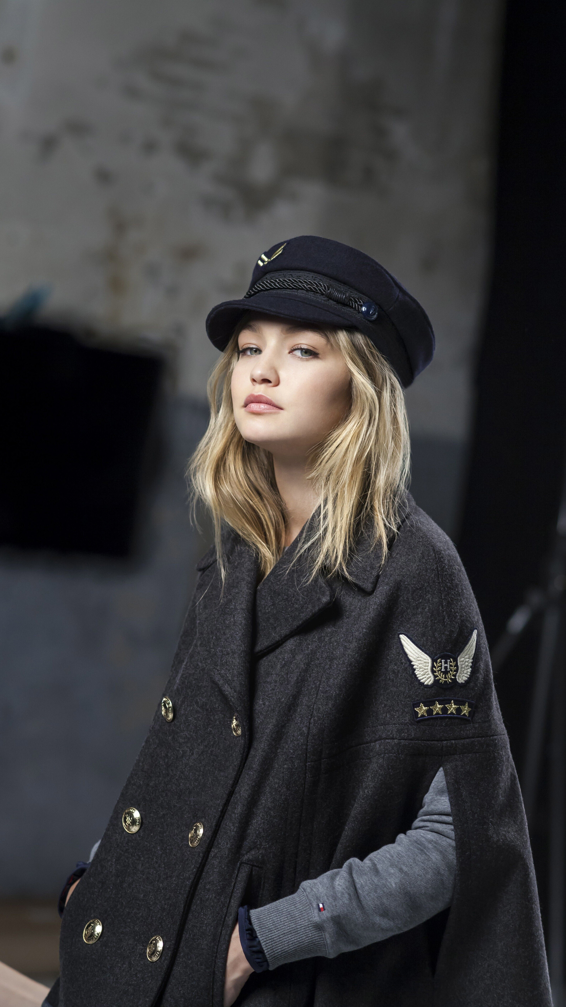 Gigi Hadid wearing a navy captain's hat and grey cape HD Phone Wallpaper