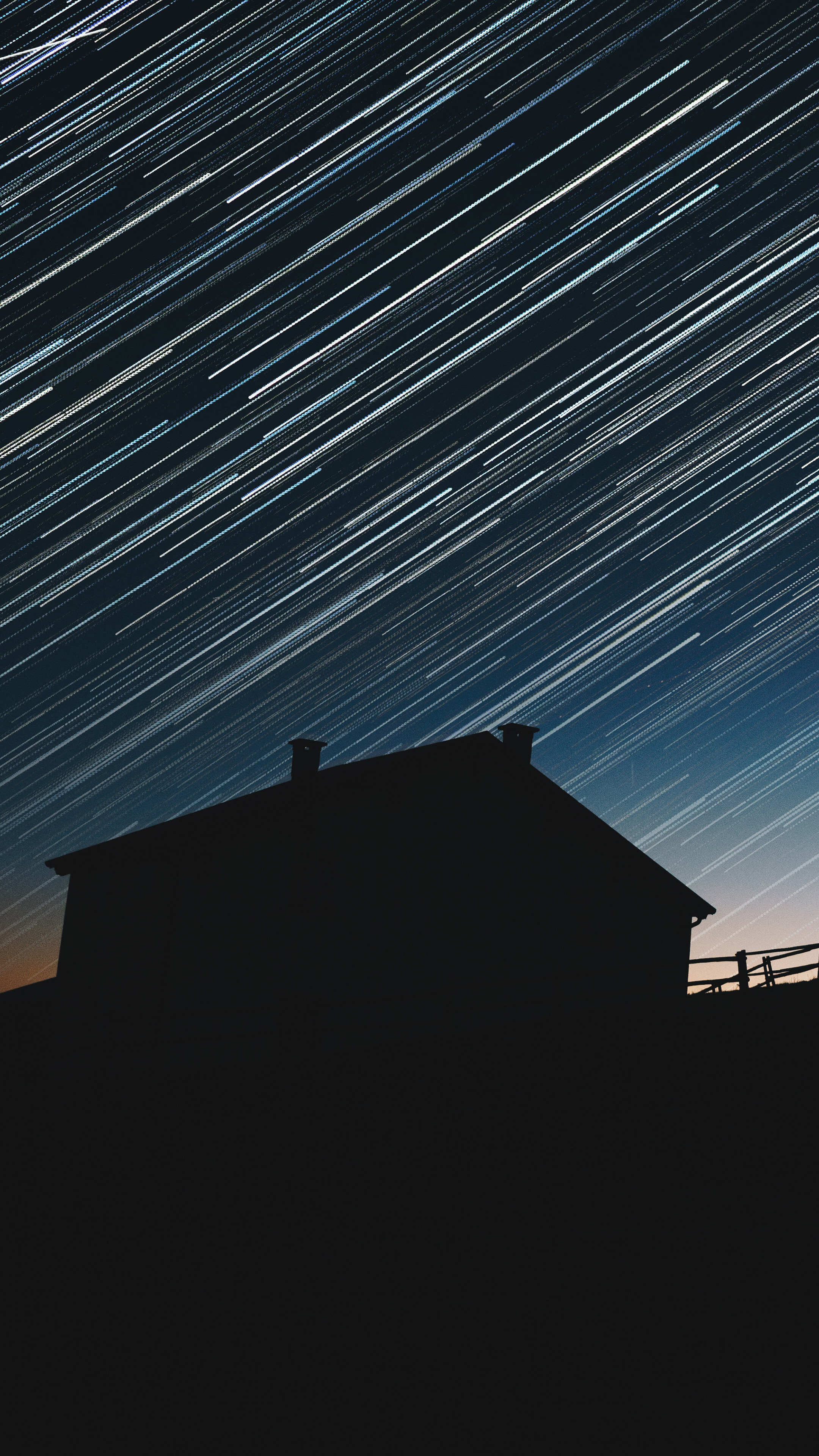 Star trails over a silhouetted house at night HD Phone Wallpaper