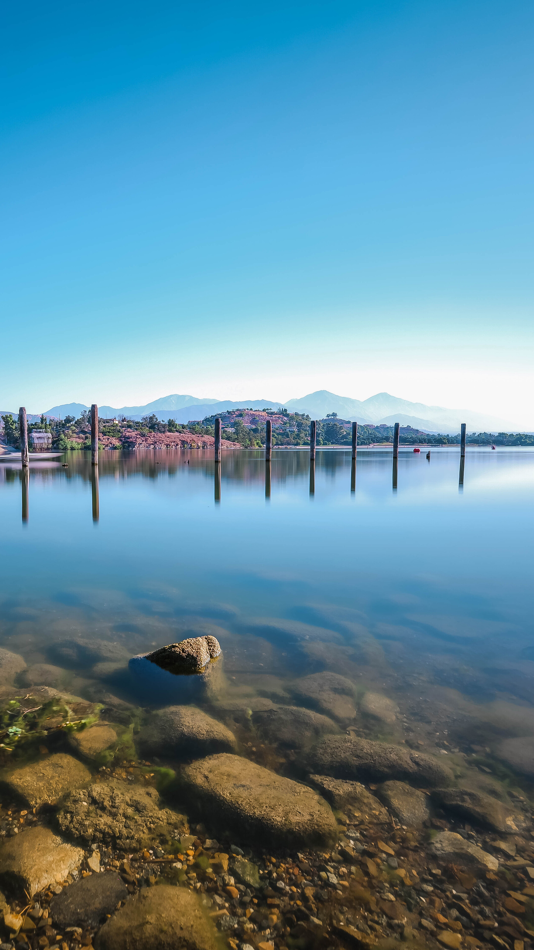 Lake with wooden posts and mountains HD Phone Wallpaper