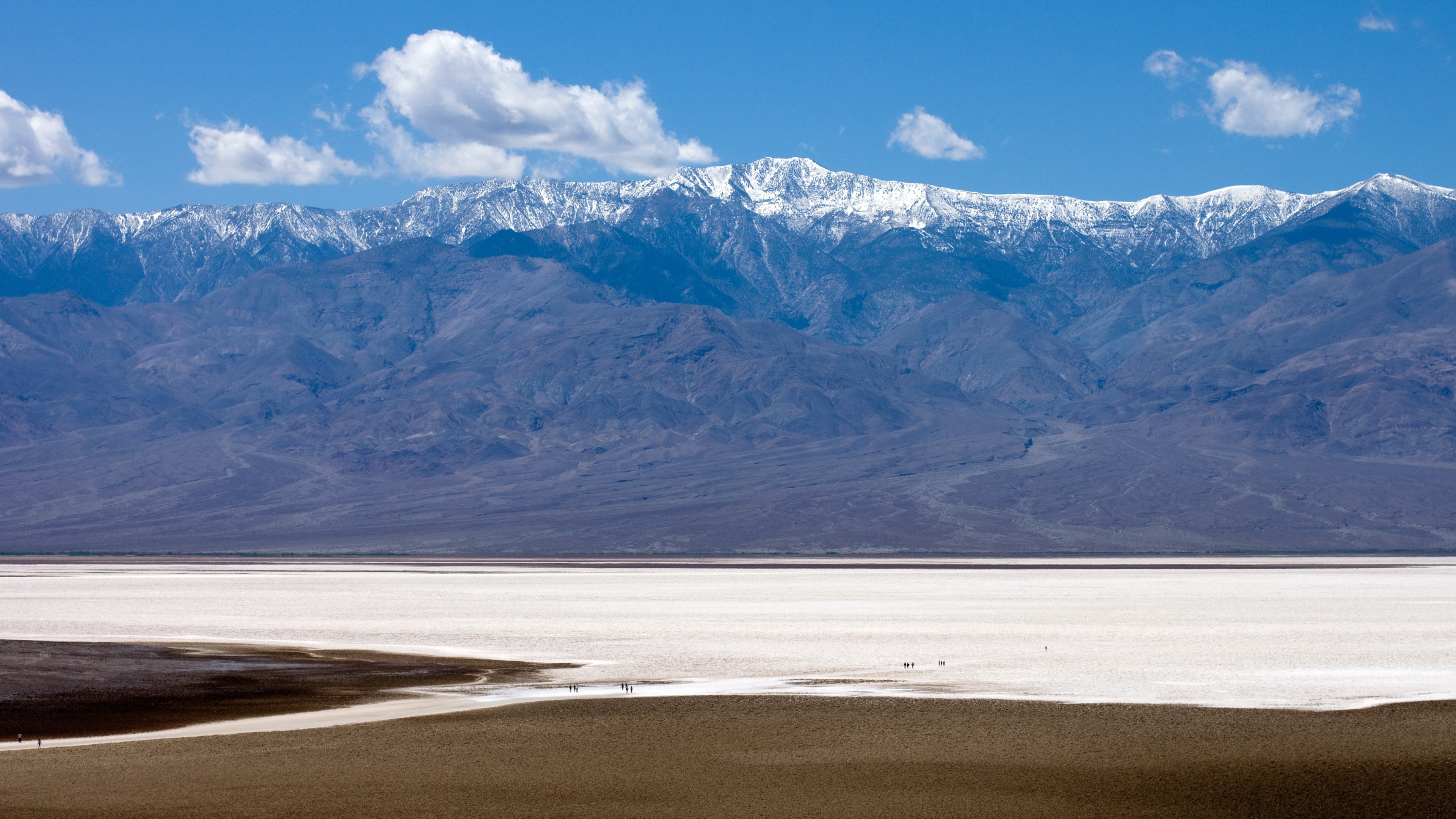 Snow-capped mountains over a salt flat HD Wallpaper