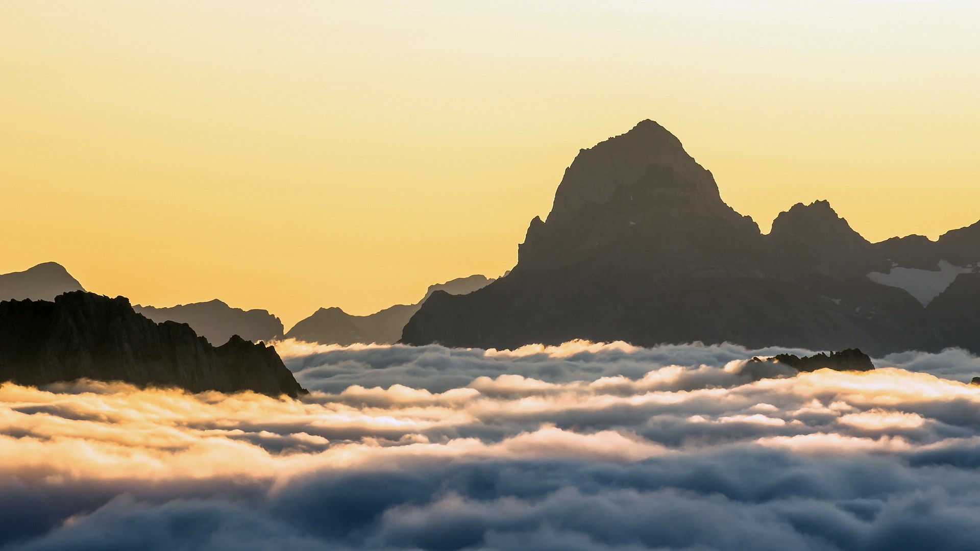 Mountain peaks above clouds at sunset HD Wallpaper