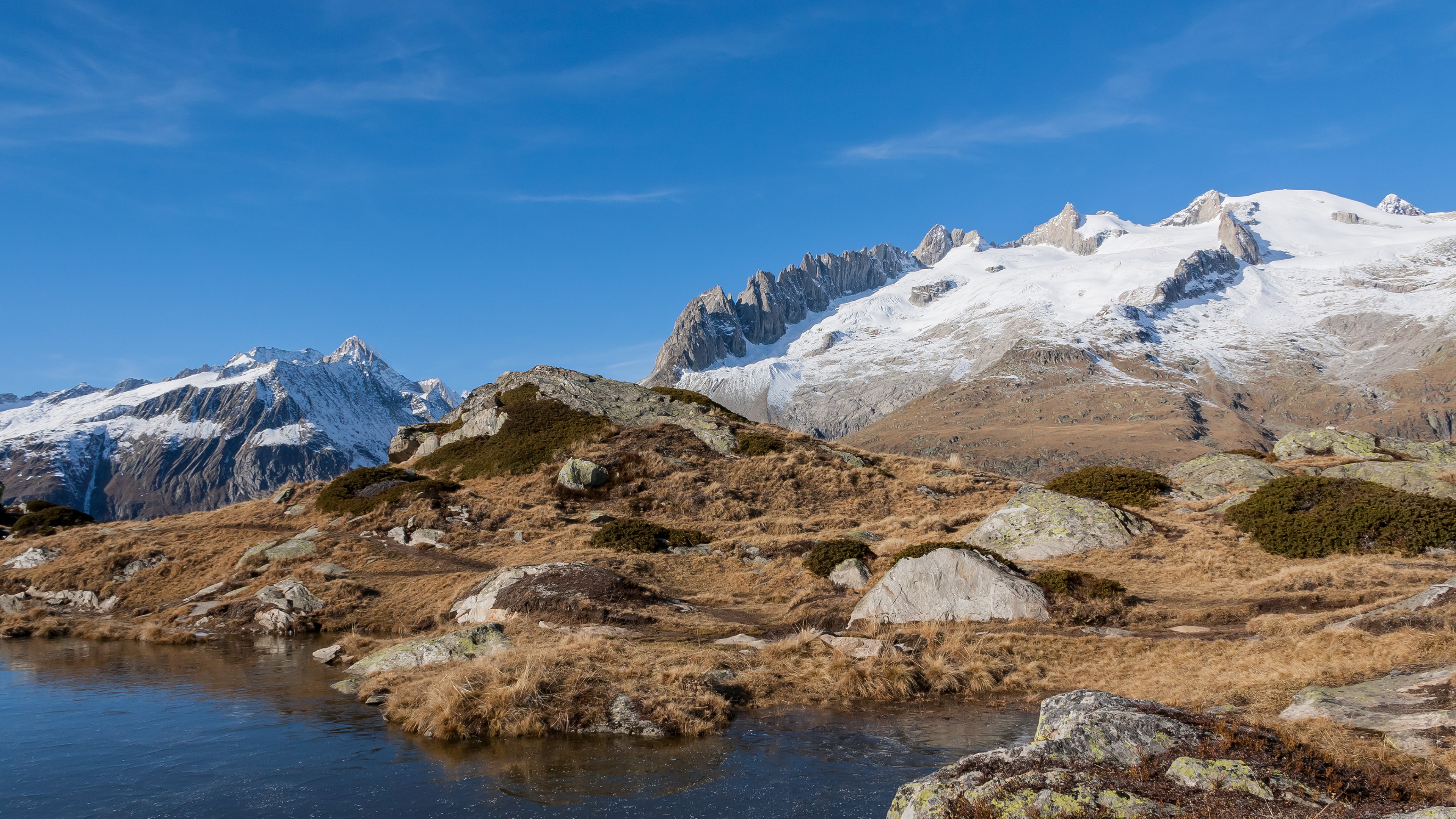 Snow-capped mountains and a frozen lake in a rocky landscape HD Wallpaper