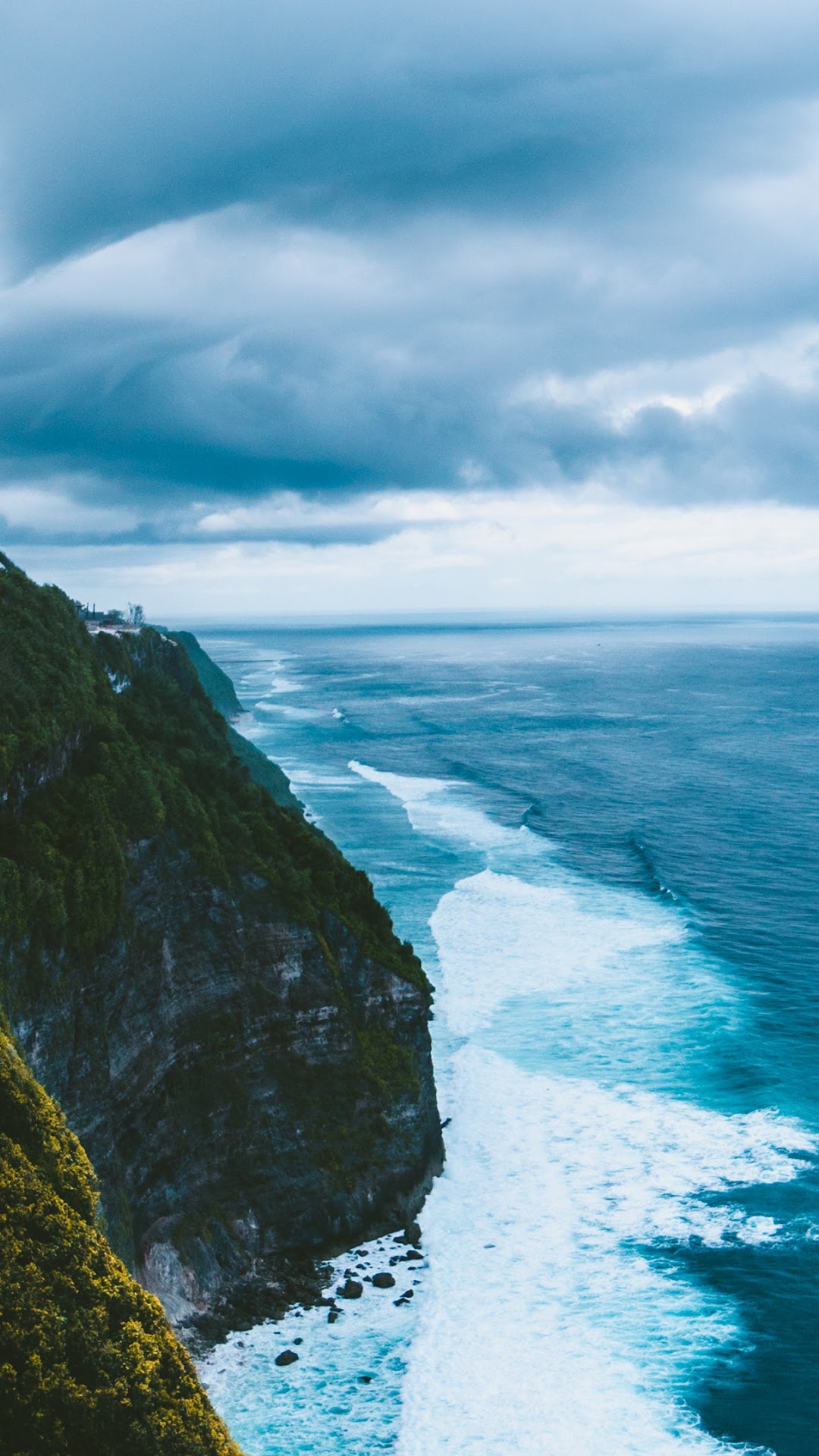 Ocean waves crashing against a cliff under cloudy sky HD Phone Wallpaper
