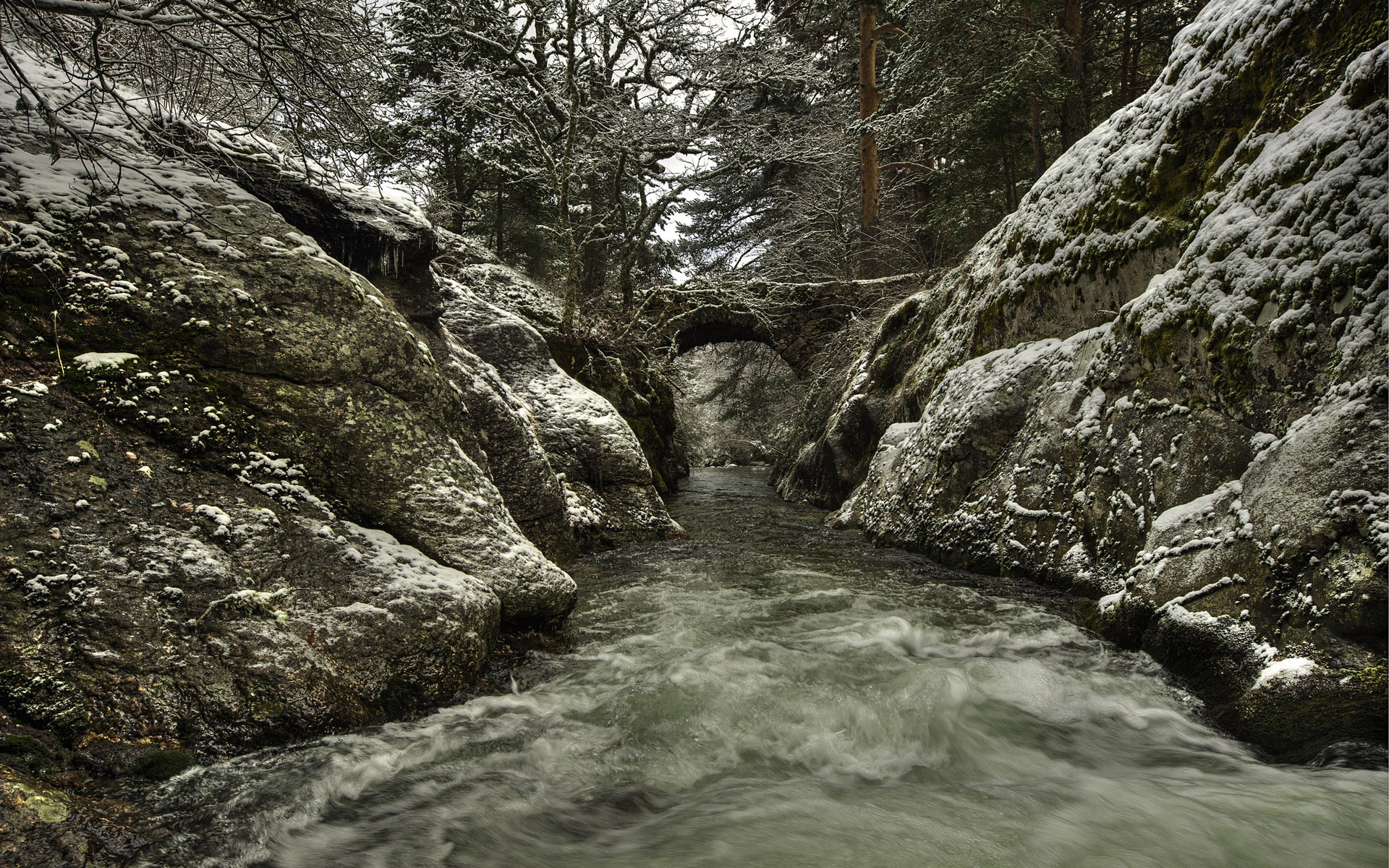 Snowy gorge with a river and an ancient stone bridge HD Wallpaper